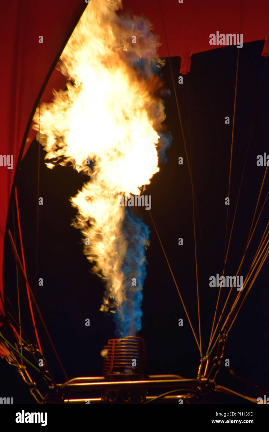 bright shining flames of a burner of a red hot air balloon, burner with a extreme hot flame light up the inside of a red hot air balloon Stock Photo