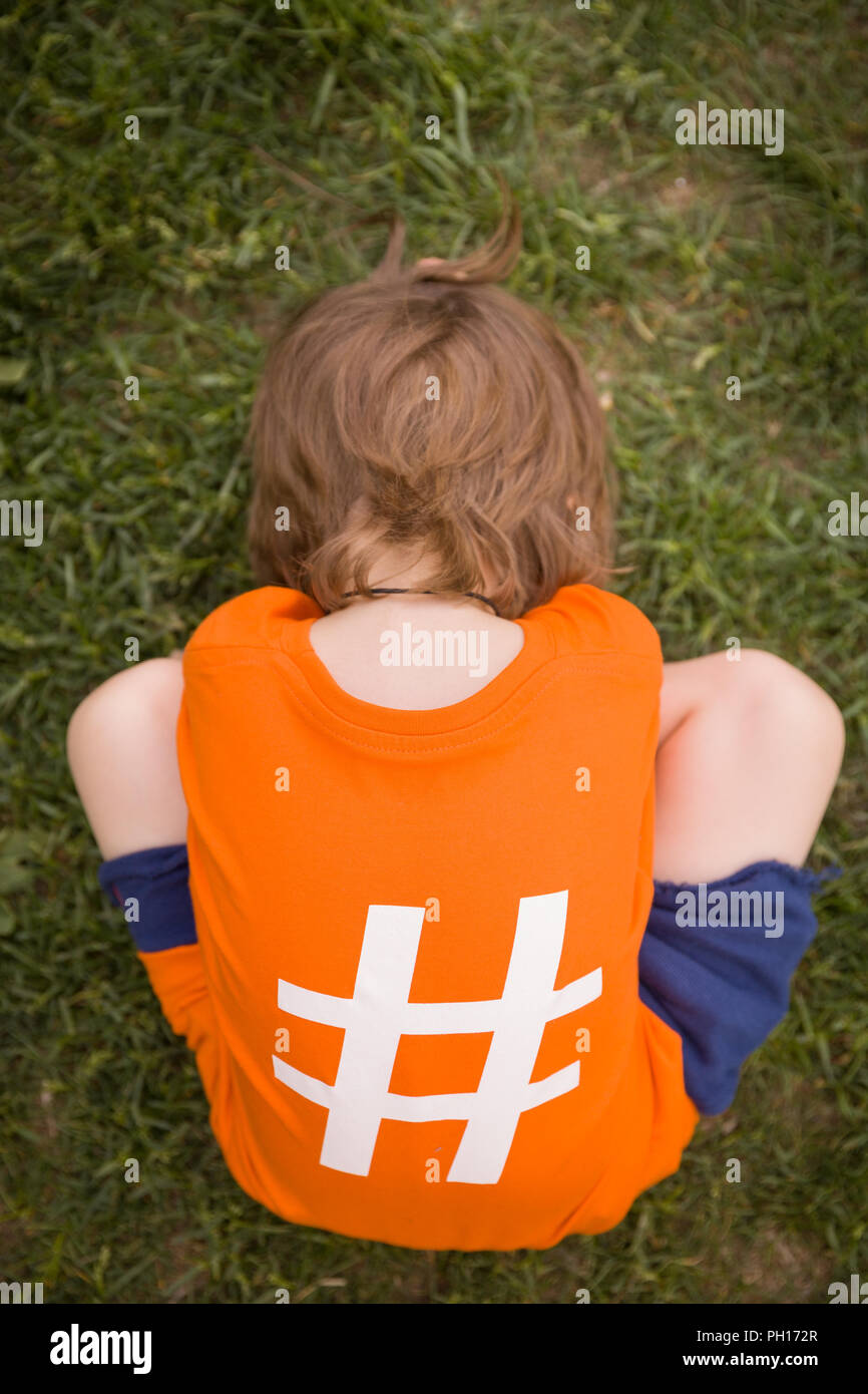 Little Sportive Kid Boy In Sport Form Sitting On The Grass Waiting For