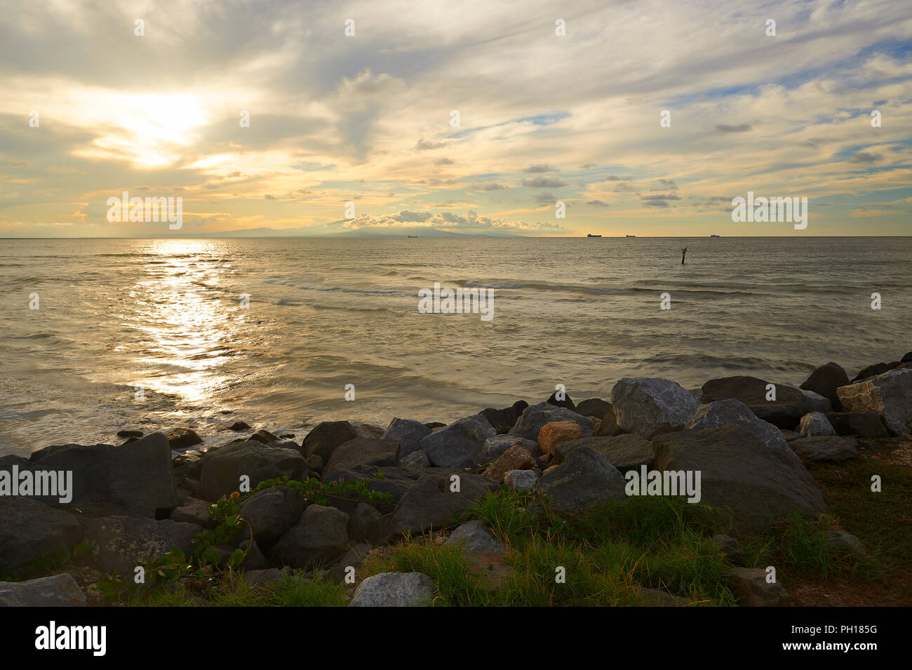 Sunset in Coatzacoalcos, Mexico. The San Martin hill, four oil tankers waiting entrance to the Pajaritos terminal, and a pelican. Stock Photo