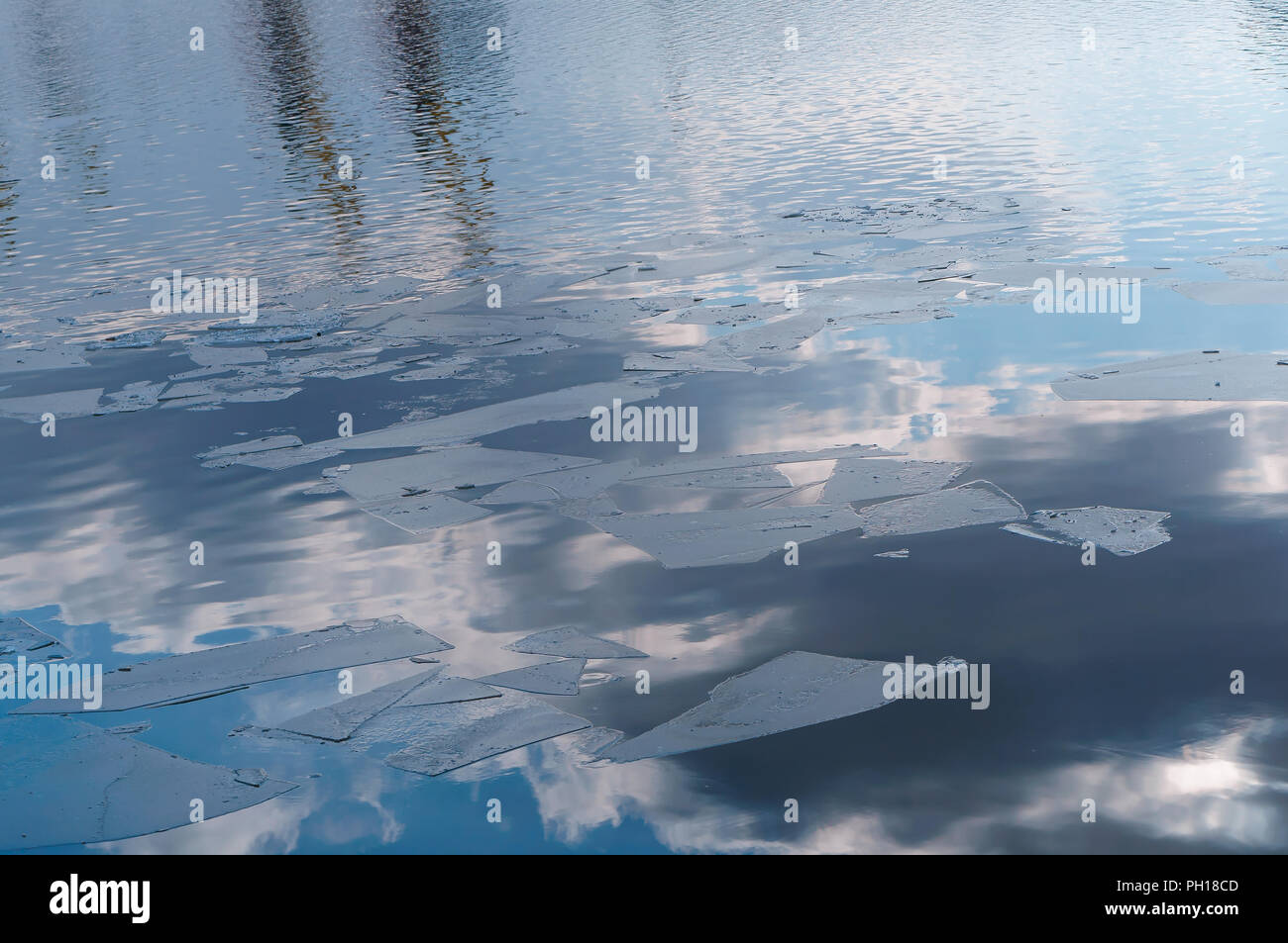 pieces of ice on the water in early spring, clouds reflected in the water Stock Photo