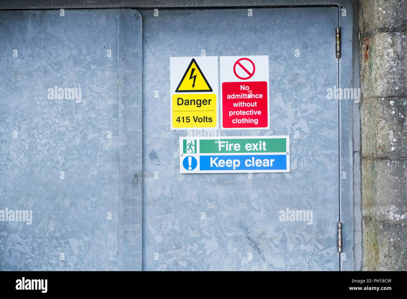 Danger high voltage keep clear fire exit sign on metal door Stock Photo
