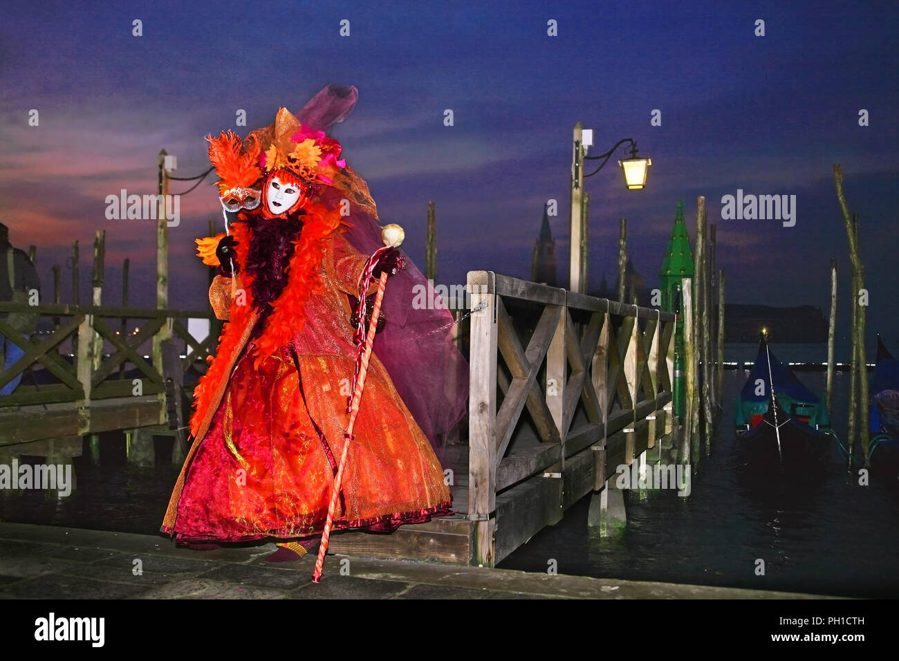 Molo San Marco, Venice, Italy: masked reveller poses in front of the Basin of St. Mark, with the Chiesa di San Giorgio Maggiore in the background Stock Photo