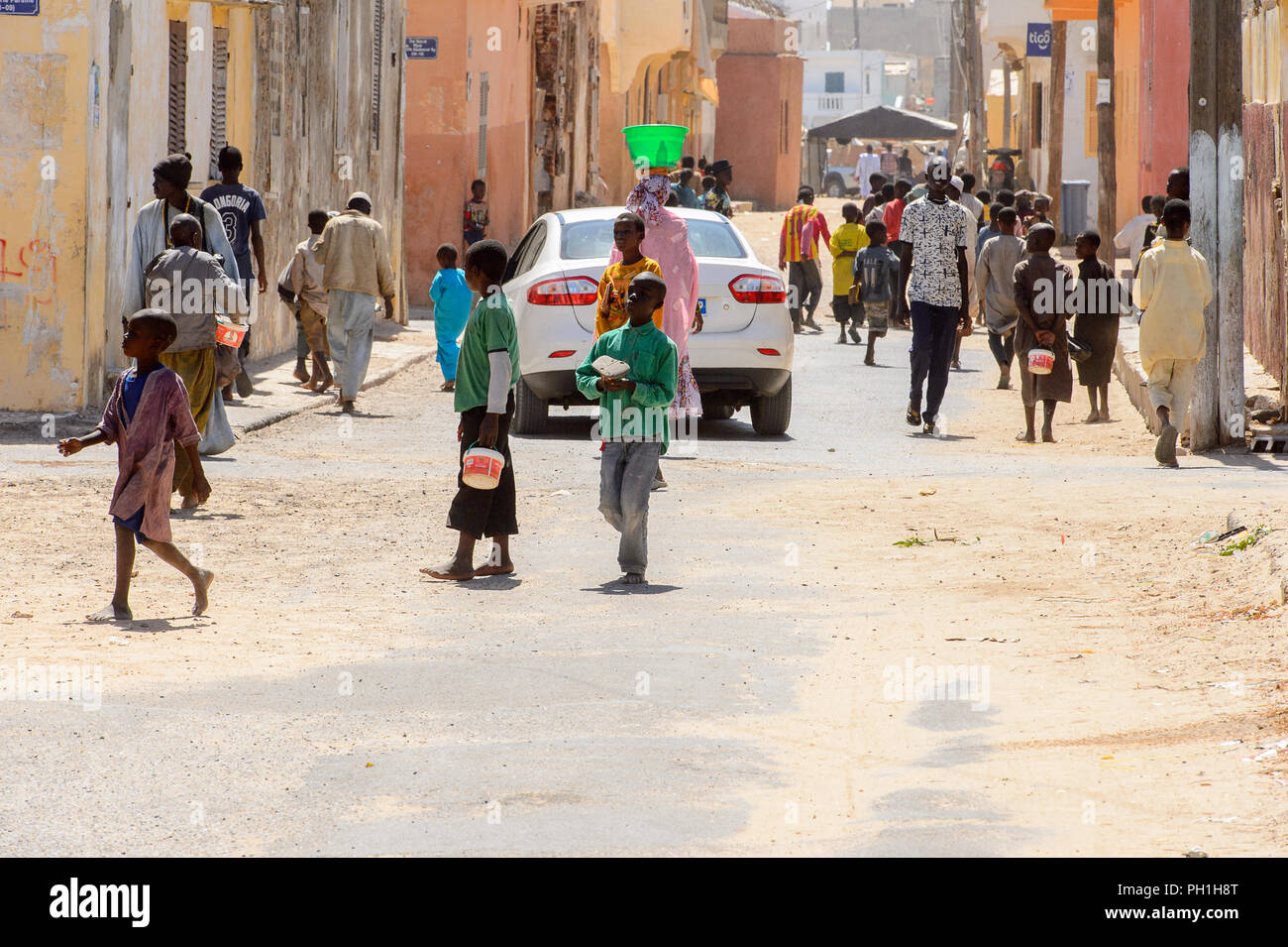 SAINT LOUIS, SENEGAL - APR 24, 2017: Unidentified Senegalese people walk along the road between buildings in Saint Louis, one of the biggest cities in Stock Photo
