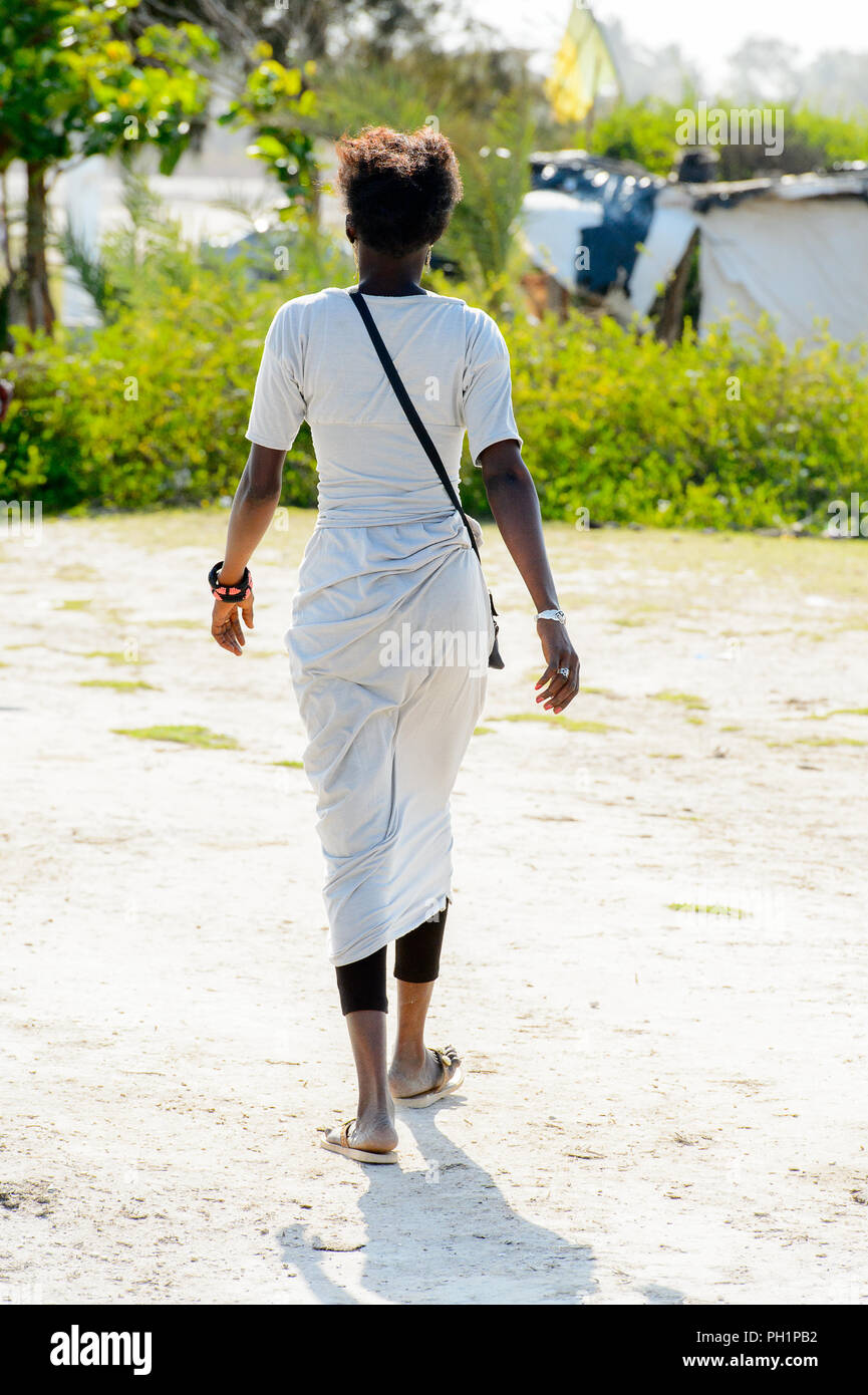 LAC ROSE, SENEGAL - APR 26, 2017: Unidentified Senegalese woman in white clothes walks from behind on the salty coast of the Lake Retba, UNESCO World  Stock Photo