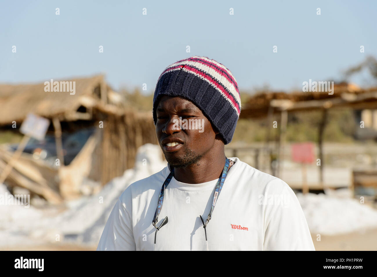 LAC ROSE, SENEGAL - APR 26, 2017: Unidentified Senegalese man in a hat and white shirt frowns on the salty coast of the Lake Retba, UNESCO World Herit Stock Photo