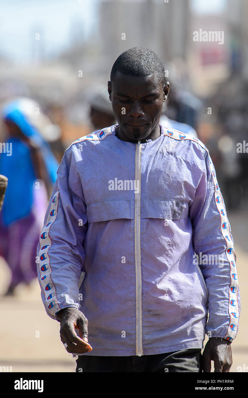 KAYAR, SENEGAL - APR 27, 2017: Unidentified Senegalese man in purple jacket walks with lowered head at the local market of Kayar, Senegal. Stock Photo