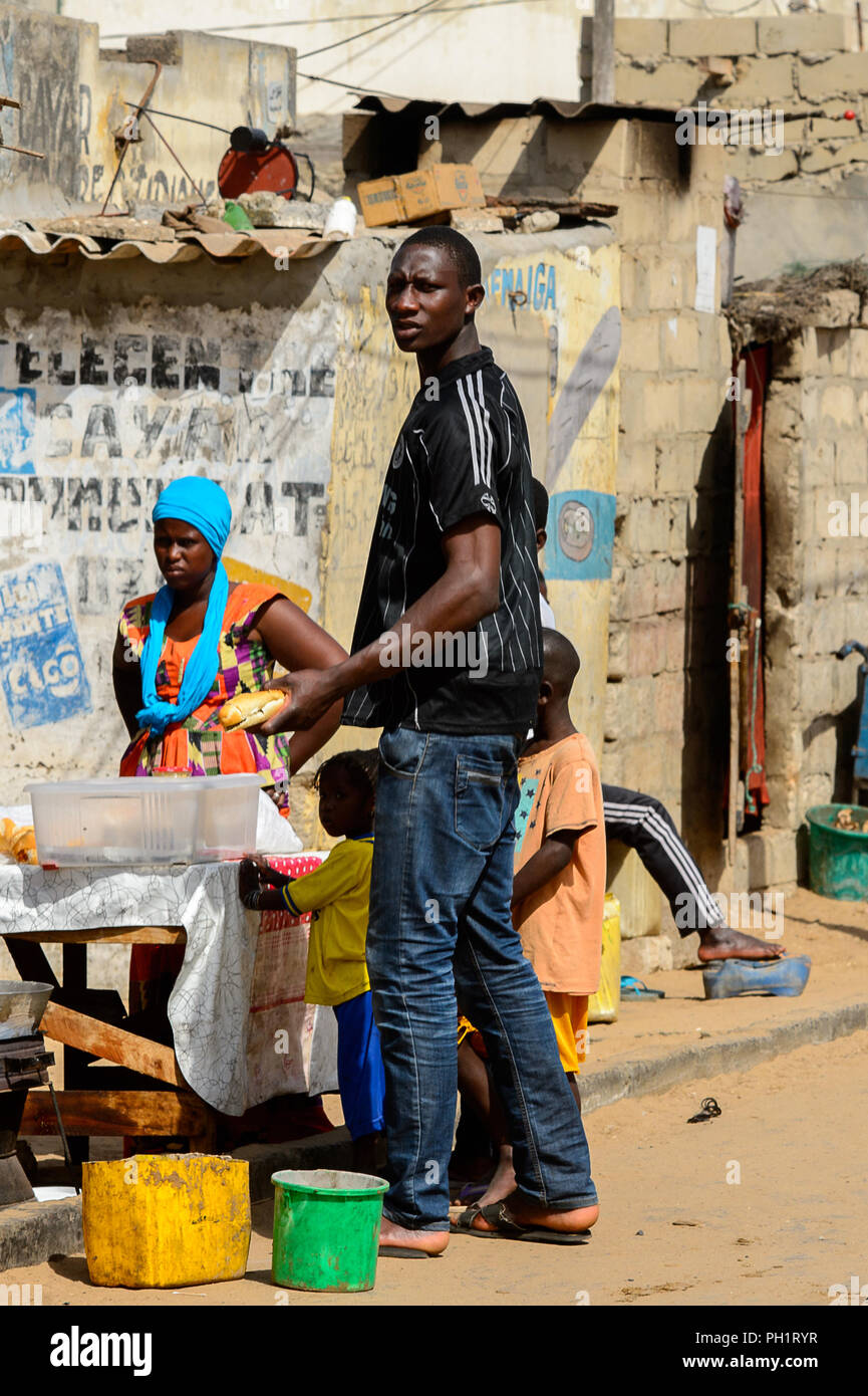 KAYAR, SENEGAL - APR 27, 2017: Unidentified Senegalese man holds a bread at the local market of Kayar, Senegal. Stock Photo