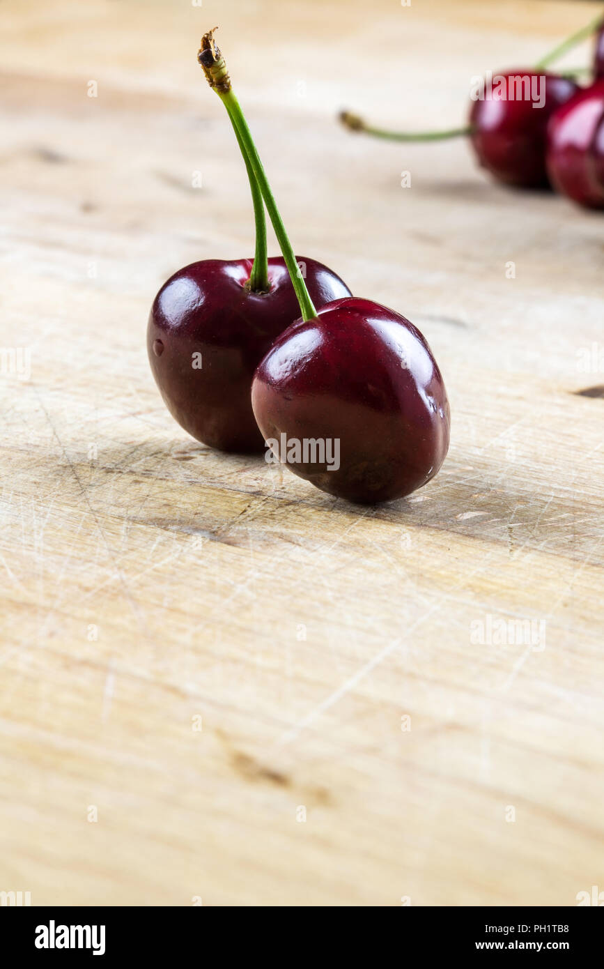 Two juicy healthy ripe red cherries rich in antioxidants on a rustic wooden table with copyspace. Stock Photo