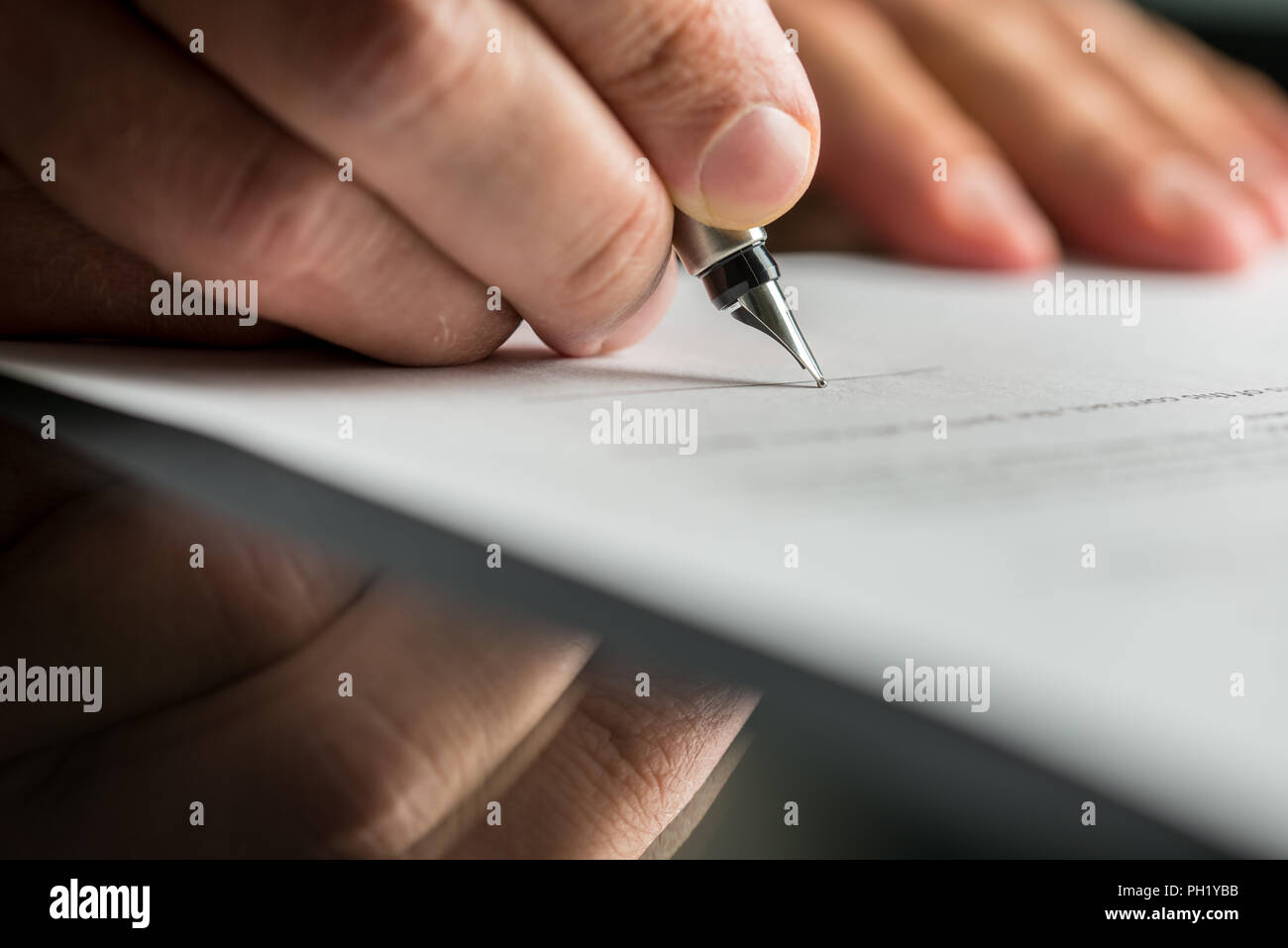 Closeup of male hand about to sign a business contract with a fountain pen. Stock Photo