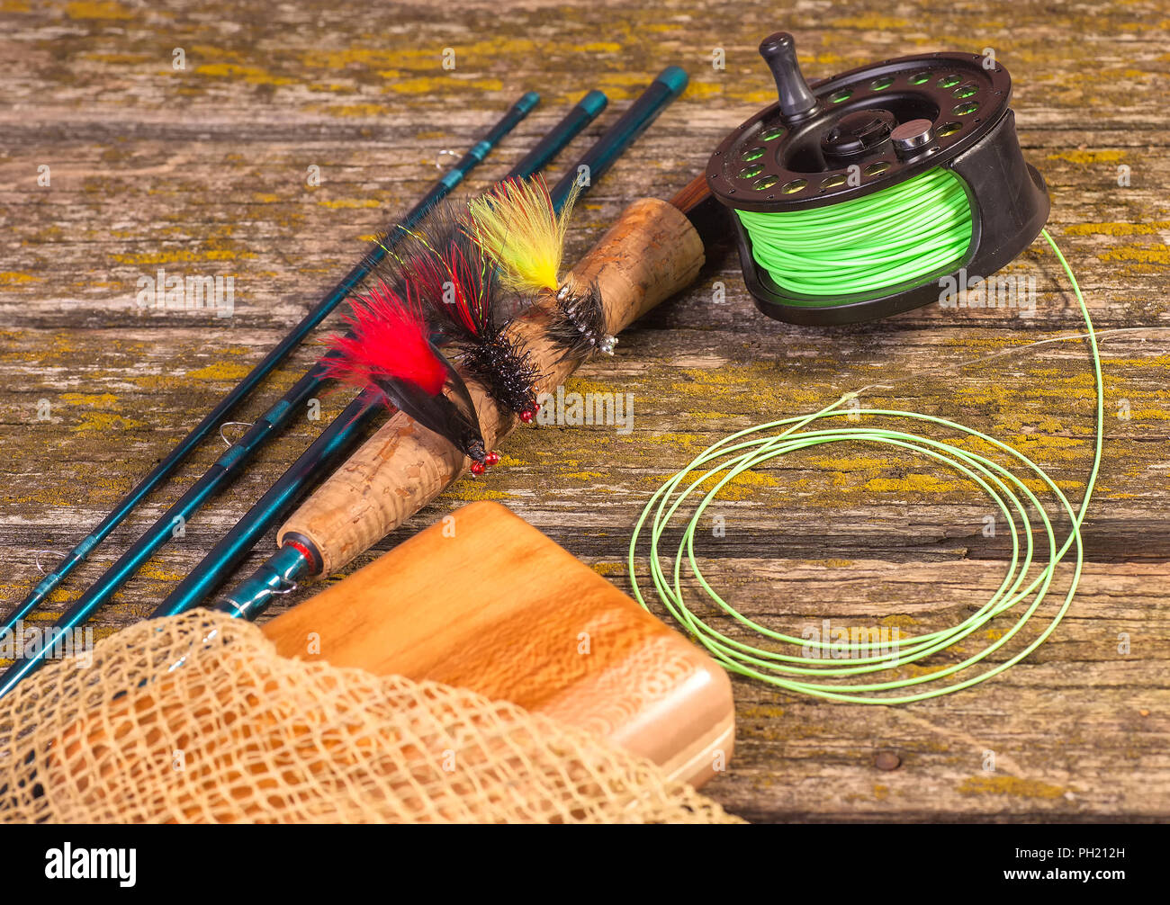 https://c8.alamy.com/comp/PH212H/fly-fishing-rod-with-a-coil-and-flies-lie-on-old-wooden-boards-PH212H.jpg