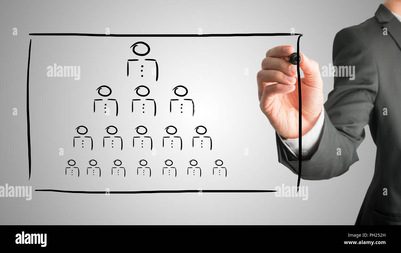 Businessman drawing a hierarchy concept on a virtual interface with a pyramid formation of people depicting the boss, leadership and work force in hum Stock Photo