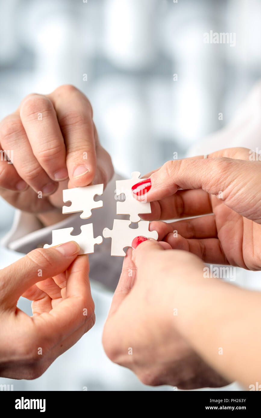 Four hands fitting together matching interlocking puzzle pieces conceptual of teamwork and