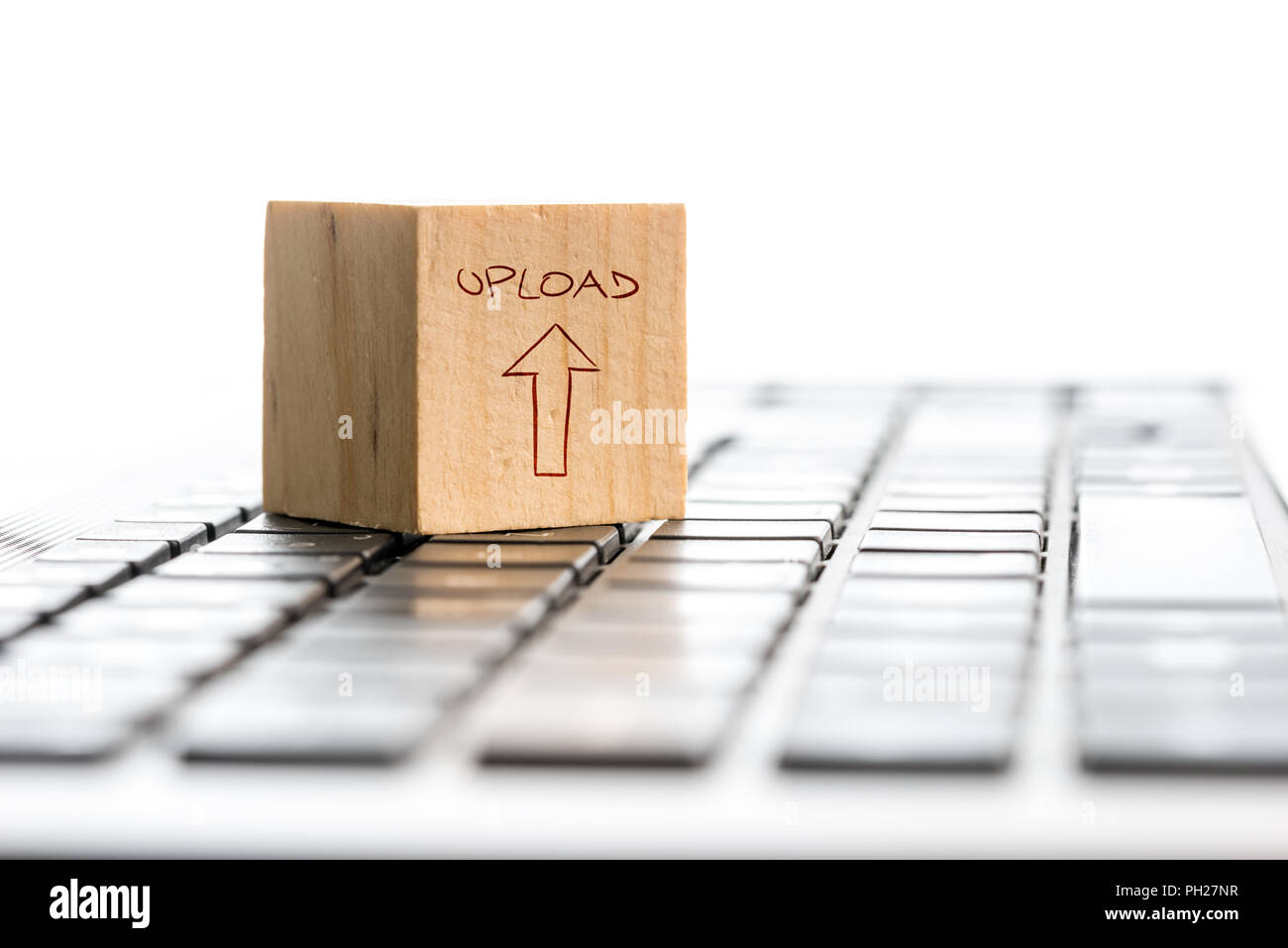 Computer Upload concept with a wooden cube with a hand-drawn arrow and word - Upload - on a white computer keyboard isolated on white with copyspace. Stock Photo