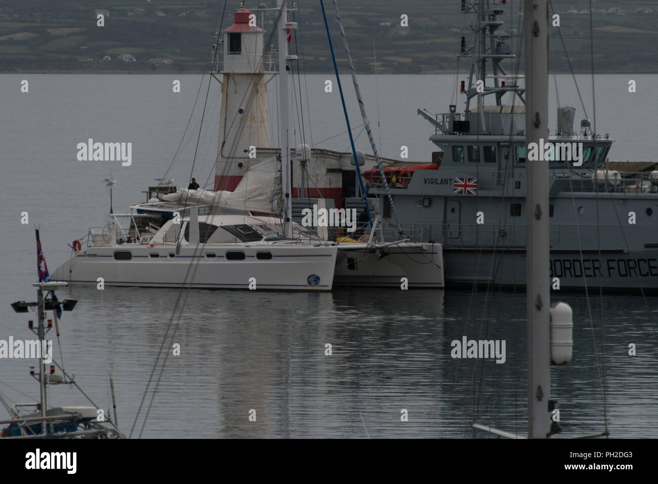 Newlyn Harbour, Cornwall, UK. 30th Aug, 2018. The border patrol vessel Vigilant was seen cruising into Newlyn harbour this morning, closely followed by a Catamaran which was berthed alongside the ship. Shortly afterwards police handcuffed and escorted off 2 men. An NCA spokesperson said: “Five men have been arrested on suspicion of drug trafficking offences and NCA officers, with support from Border Force Maritime and Deep Rummage specialists, are at Newlyn harbour, as investigation continues”. Credit: Simon Maycock/Alamy Live News Stock Photo