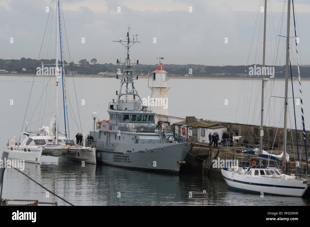 Newlyn Harbour, Cornwall, UK. 30th Aug, 2018. The border patrol vessel Vigilant was seen cruising into Newlyn harbour this morning, closely followed by a Catamaran which was berthed alongside the ship. Shortly afterwards police handcuffed and escorted off 2 men. An NCA spokesperson said: “Five men have been arrested on suspicion of drug trafficking offences and NCA officers, with support from Border Force Maritime and Deep Rummage specialists, are at Newlyn harbour, as investigation continues'. Credit: Simon Maycock/Alamy Live News Stock Photo