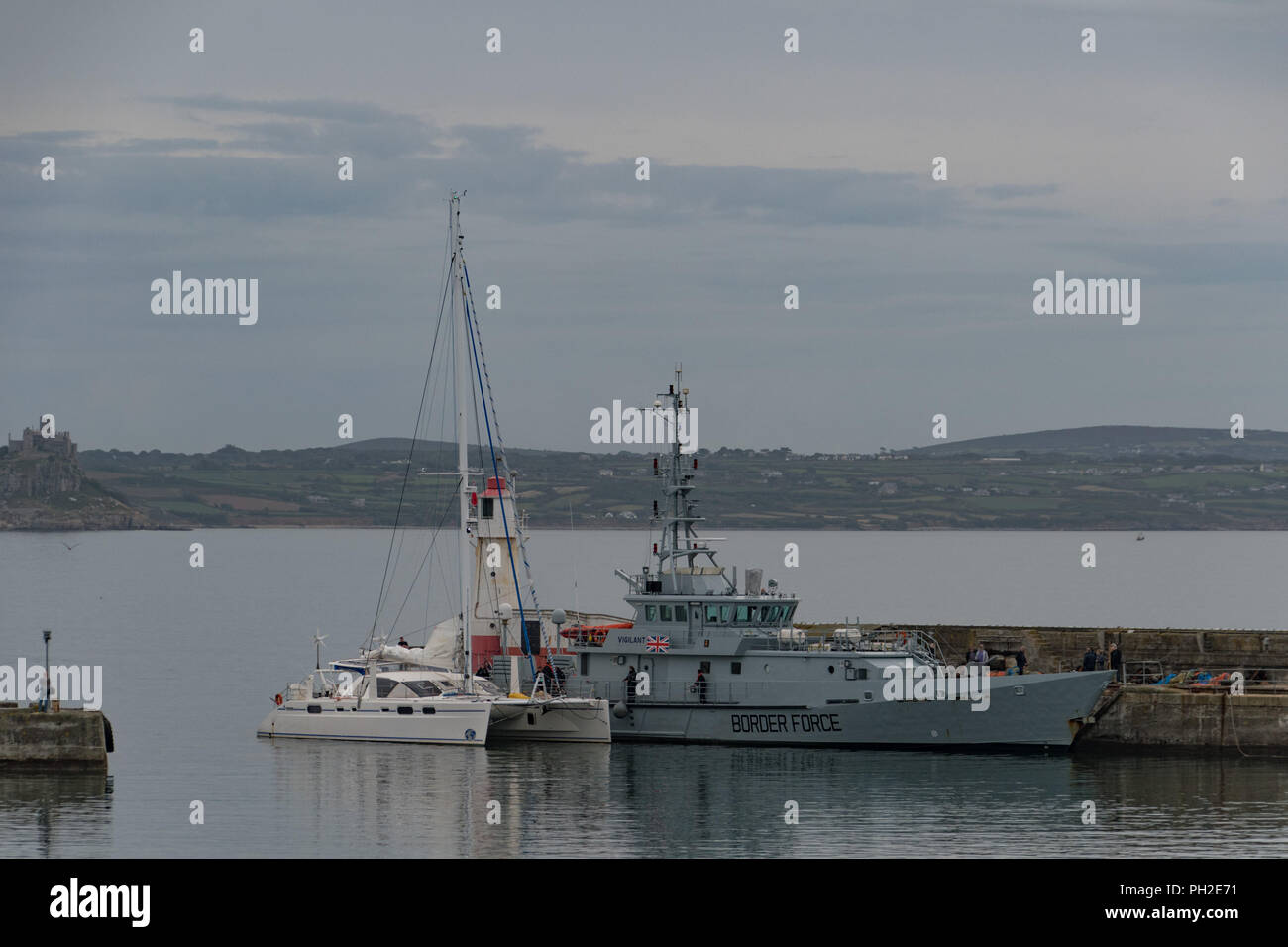 Newlyn Harbour, Cornwall, UK. 30th Aug, 2018. The border patrol vessel Vigilant was seen cruising into Newlyn harbour this morning, closely followed by a Catamaran which was berthed alongside the ship. Shortly afterwards police handcuffed and escorted off 2 men. An NCA spokesperson said: “Five men have been arrested on suspicion of drug trafficking offences and NCA officers, with support from Border Force Maritime and Deep Rummage specialists, are at Newlyn harbour, as investigation continues". Credit: Simon Maycock/Alamy Live News Stock Photo