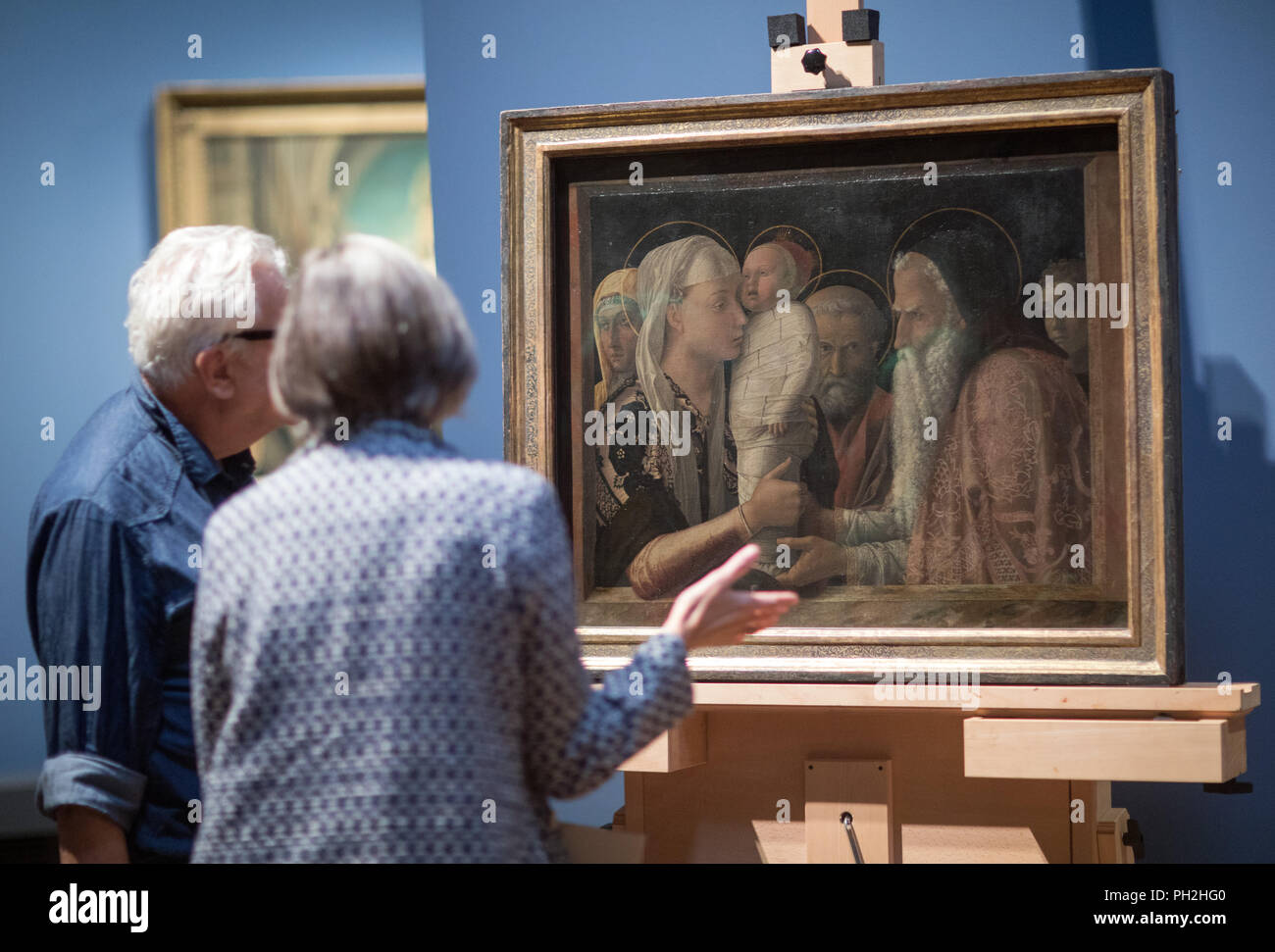 30.08.2018, Berlin: Participants of a press conference stand in front of Andrea Mantegna's painting 'The Presentation of Christ in the Temple' (c. 1453) in the collection of paintings of the National Museums in Berlin. The pictures are being prepared for transport to an exhibition in London. A press conference will provide information about the exhibition planned in Berlin and London on the work of the two Renaissance artists Giovanni Bellini (c. 1435-1516) and Andrea Mantegna (c. 1431-1506). For the show, the National Museums in Berlin and the National Gallery in London are cooperating with t Stock Photo