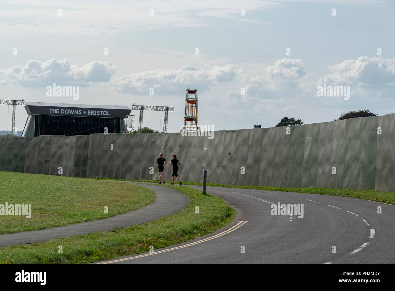 Bristol, United Kingdom, 30 August, 2018: Runners check out preparations for The Downs, Bristol concert as they pass by the security barrier erected around the site for the event.  The open air concert, a key fixture in the Bristol summer calendar, is to be staged on 1 September, 2018.  The event features music from Noel Gallagher's High Flying Birds and Paul Weller amongst a packed line-up.  Credit: mfimage/Alamy Live News Stock Photo