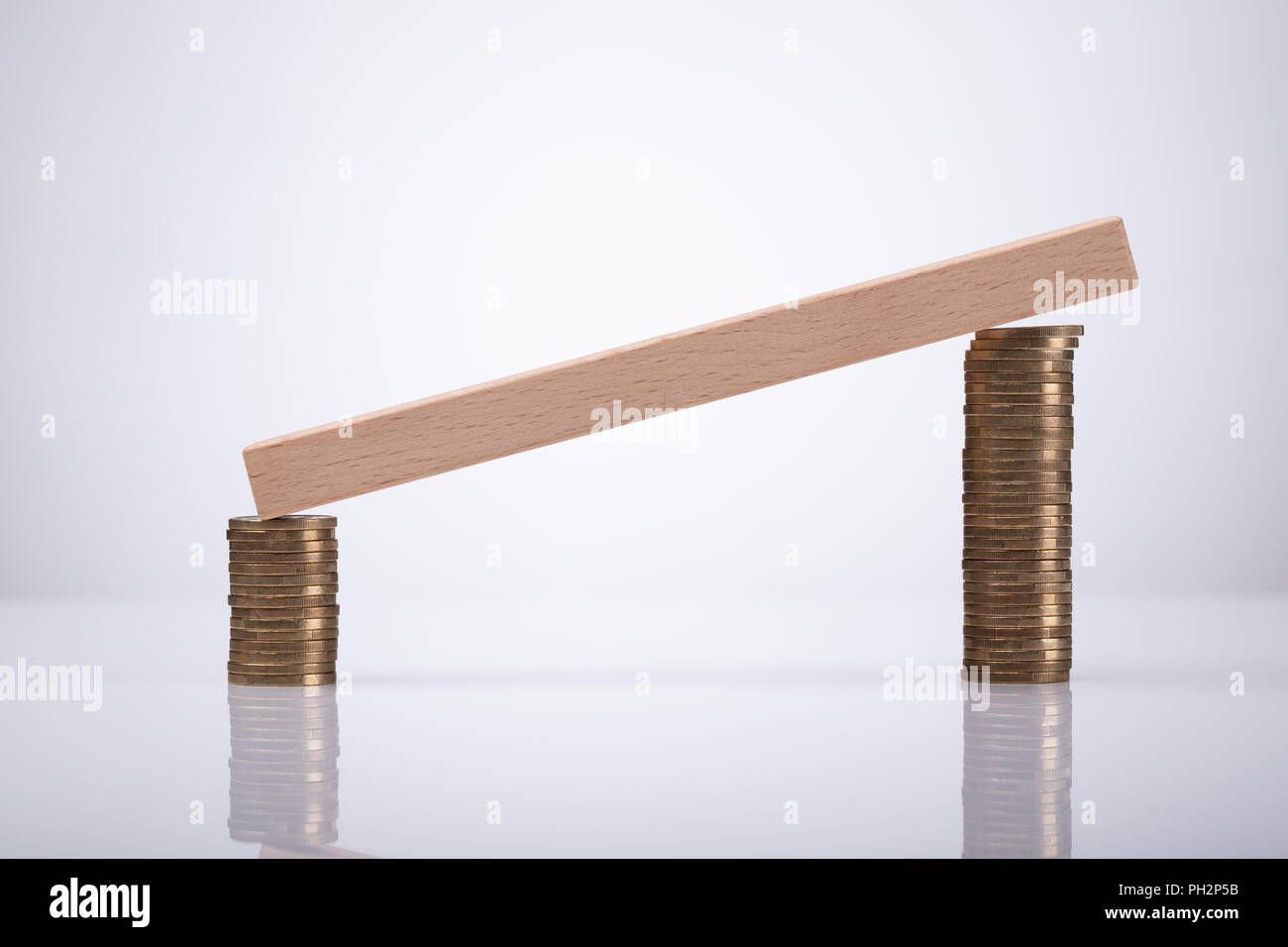 Wooden Block Over Stacked Coins Over Reflective Desk Stock Photo - Alamy