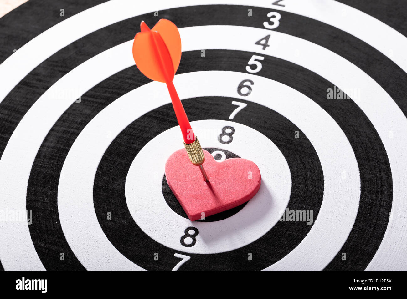 Orange Dart Arrow Hits On Red Heart Shape On Dartboard Stock Photo