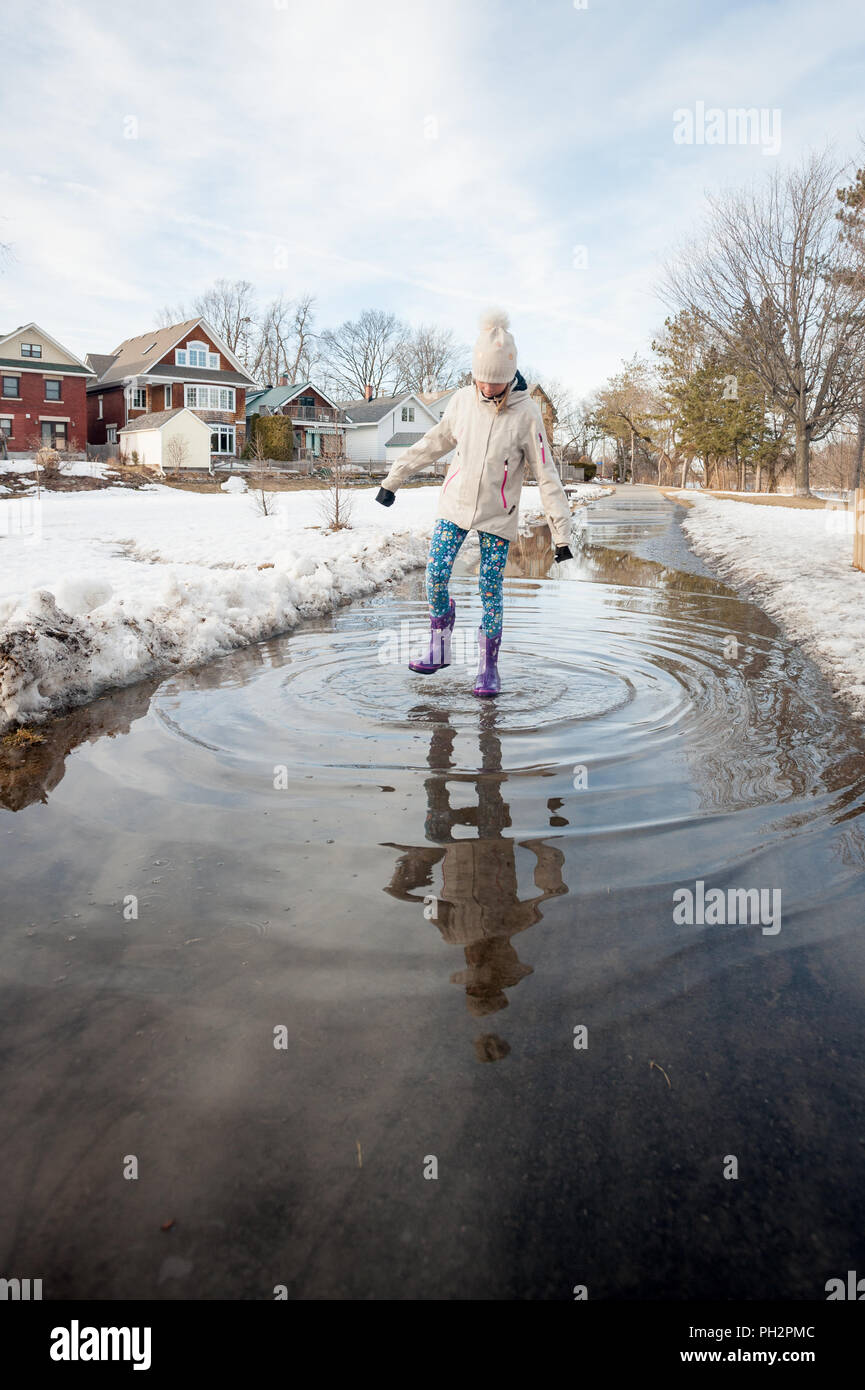 Child walking on path flooded with meltwater, Windsor Park, Ottawa, Ontario, Canada Stock Photo