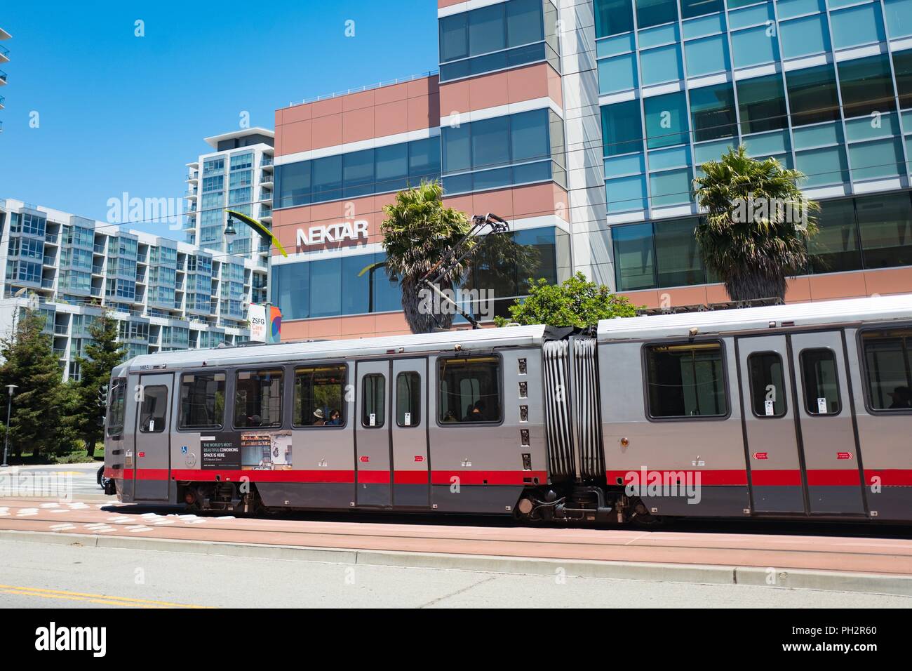 San Francisco Municipal Railroad (MUNI) train passing by the headquarters of pharmaceutical company Nektar in the Mission Bay neighborhood of San Francisco, California, July 11, 2018. () Stock Photo