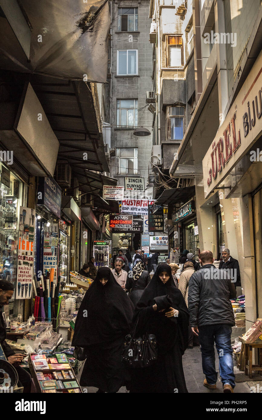 ISTANBUL, TURKEY - DECEMBER 28, 2015: Two muslim women wearing the modest clothing with the traditional scarf is passing in the middle of the spice ma Stock Photo
