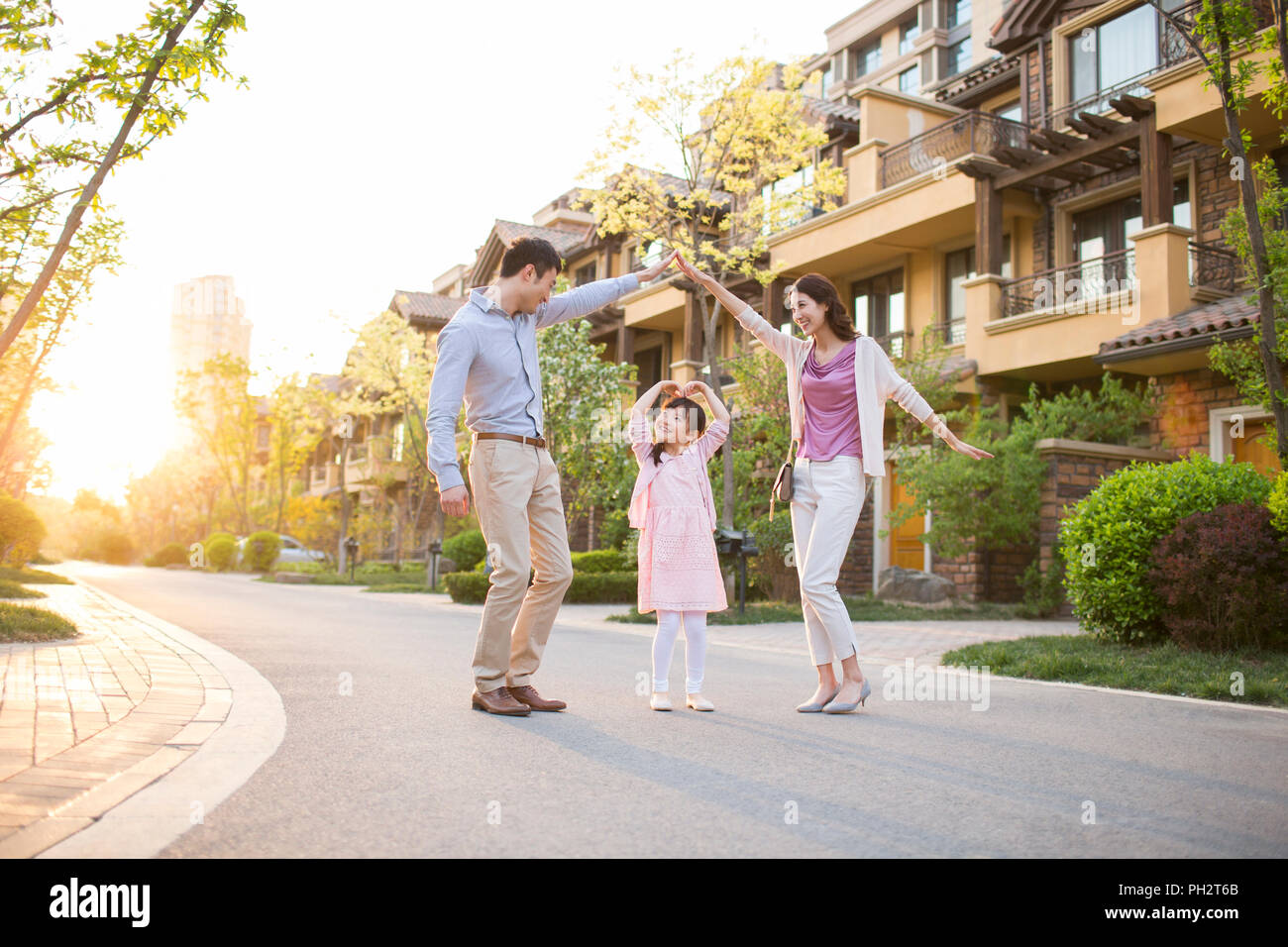Happy young family standing in front of their new house Stock Photo - Alamy