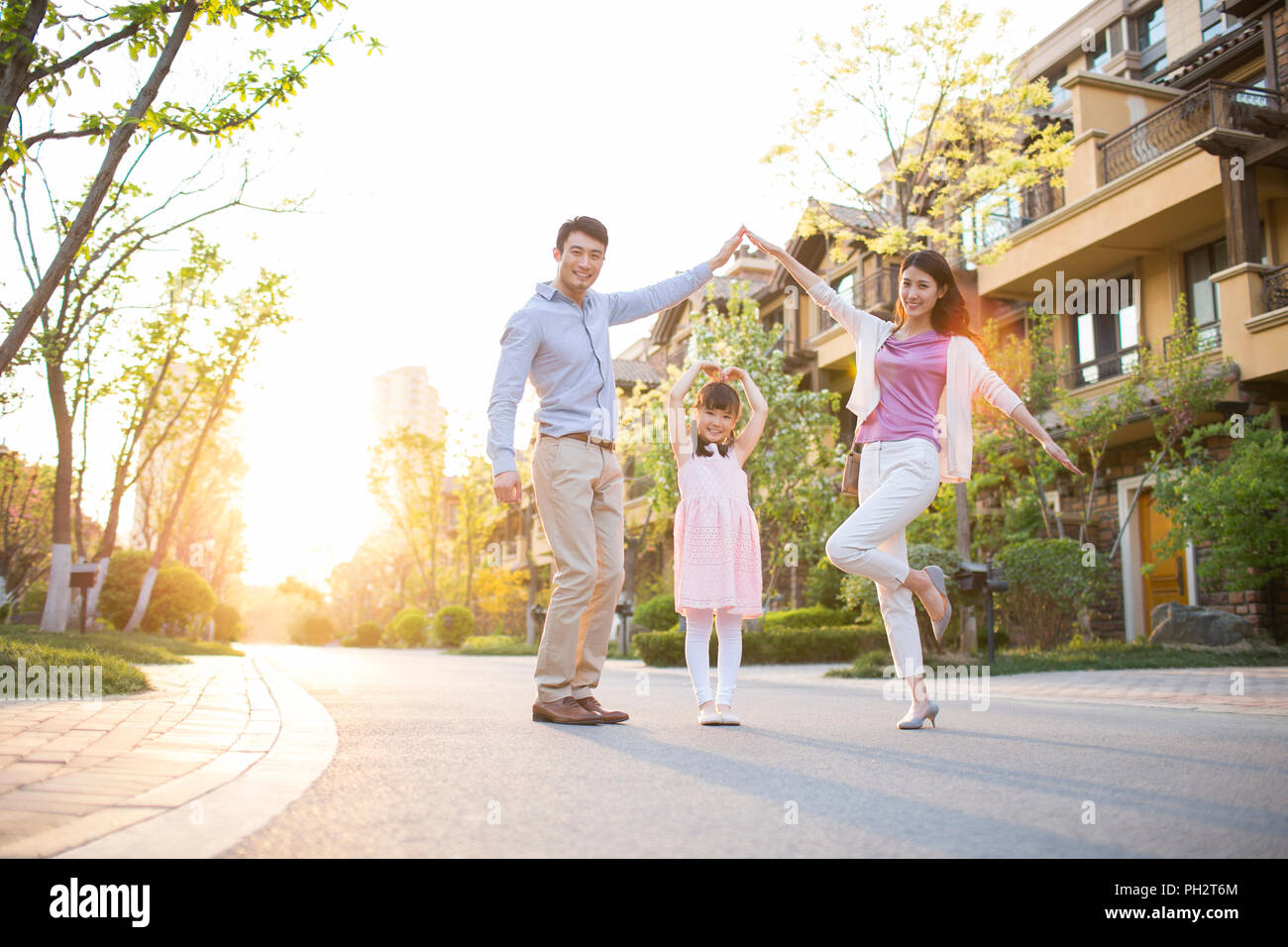 Happy young family standing in front of their new house Stock Photo - Alamy