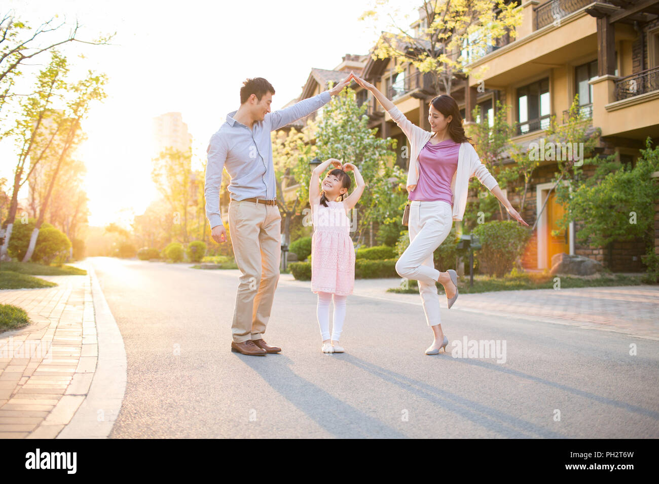 Happy young family standing in front of their new house Stock Photo - Alamy