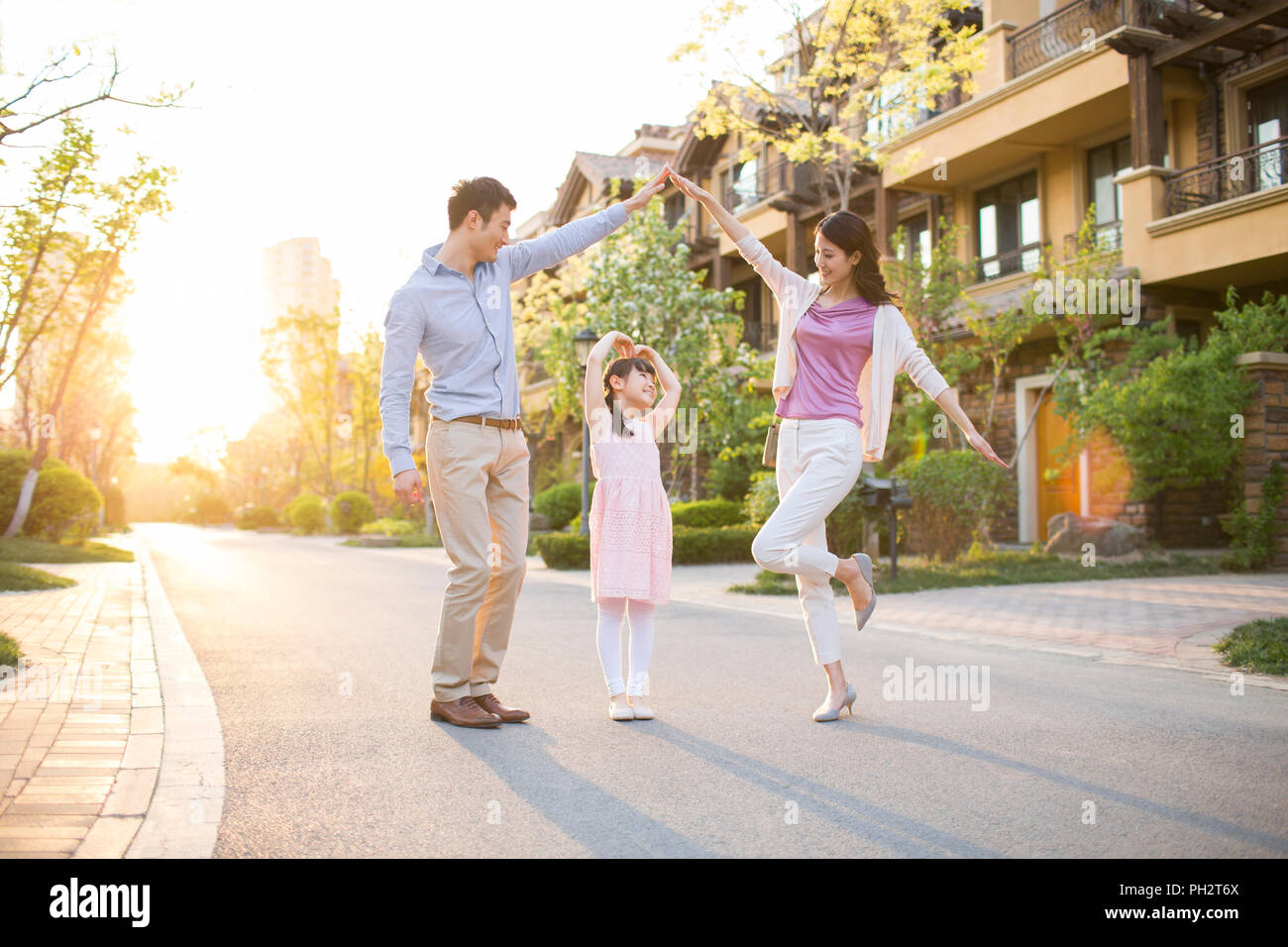 Happy young family standing in front of their new house Stock Photo - Alamy