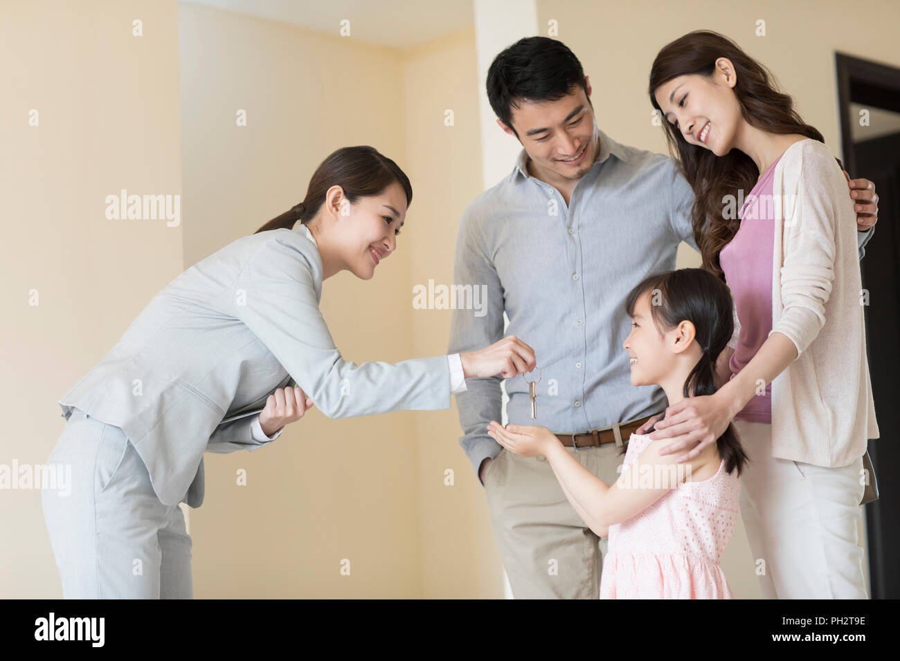 Realtor giving young family keys to new house Stock Photo - Alamy