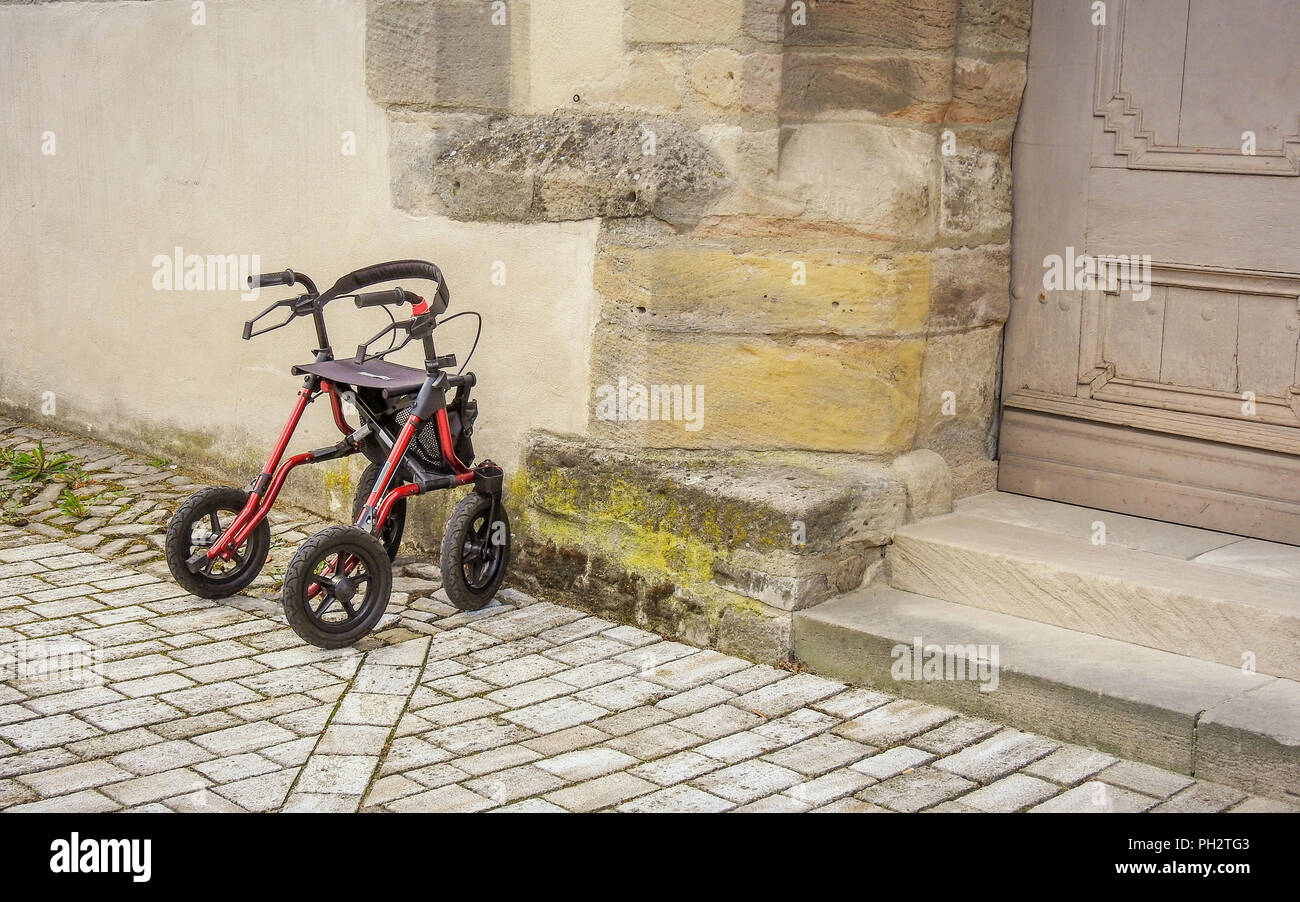 Single wheeled walker or rollator parked in front of the church entrance Stock Photo