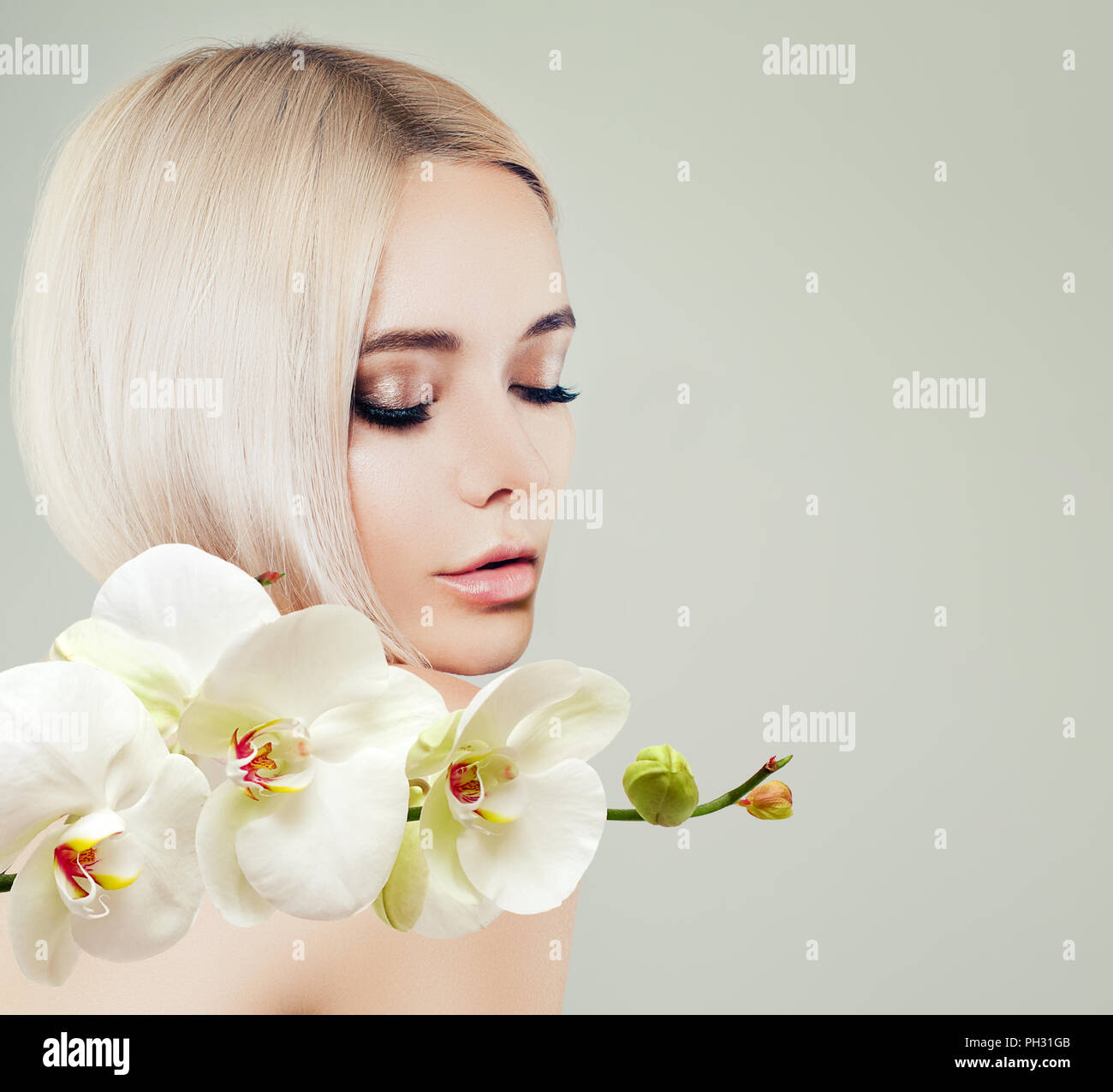 Young cute woman spa model with healthy skin and white orchid flowers. Facial treatment, cosmetology, beauty salon, skin care and spa background Stock Photo