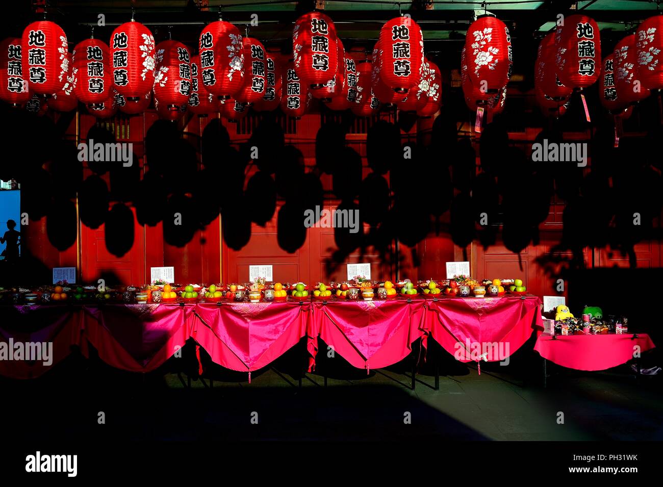 Tables with offerings and red Chinese hanging lanterns to celebrate Hungry Ghost Festival and Mid Autumn festival in Chinatown Stock Photo