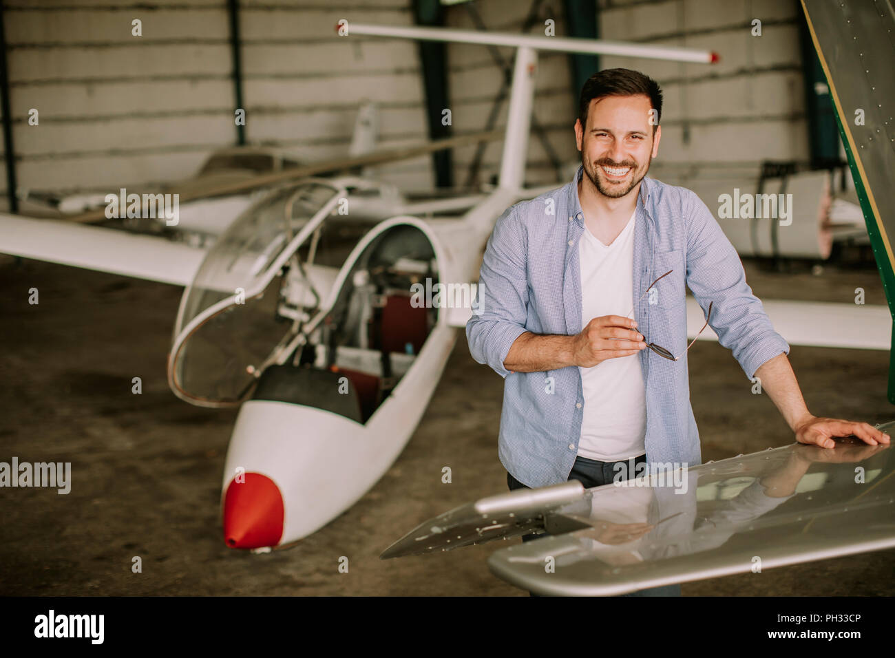 Handsome young pilot checking airplane  in the hangar Stock Photo