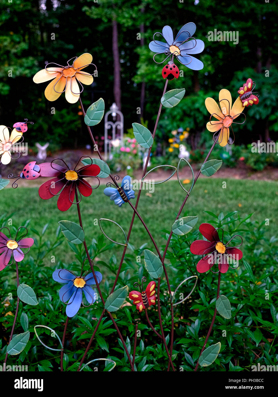 Colorful garden art in a suburban residential home garden using metal daisy like flowers. Stock Photo