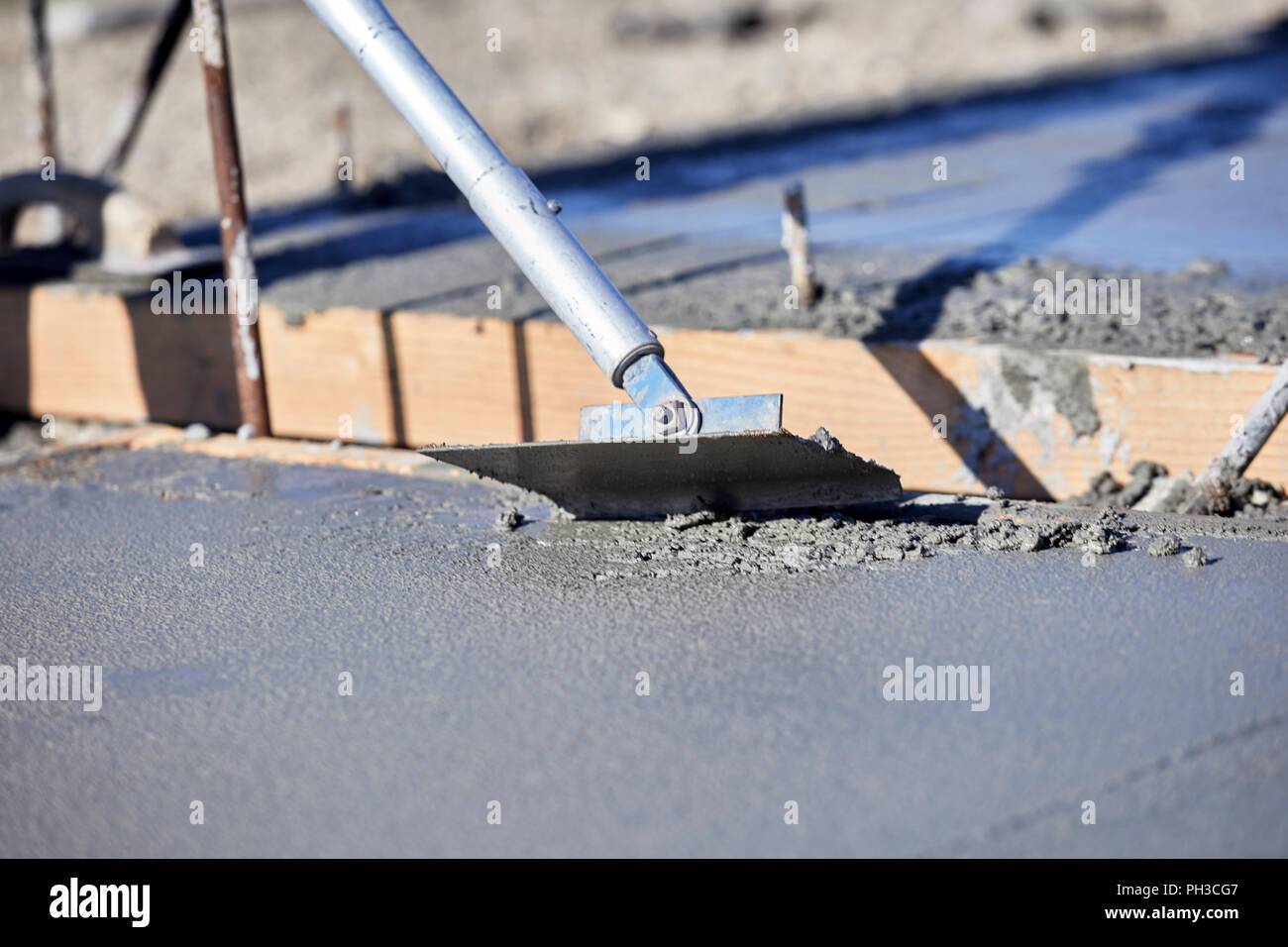 A mason using a concrete groover to finish a newly poured concrete slab