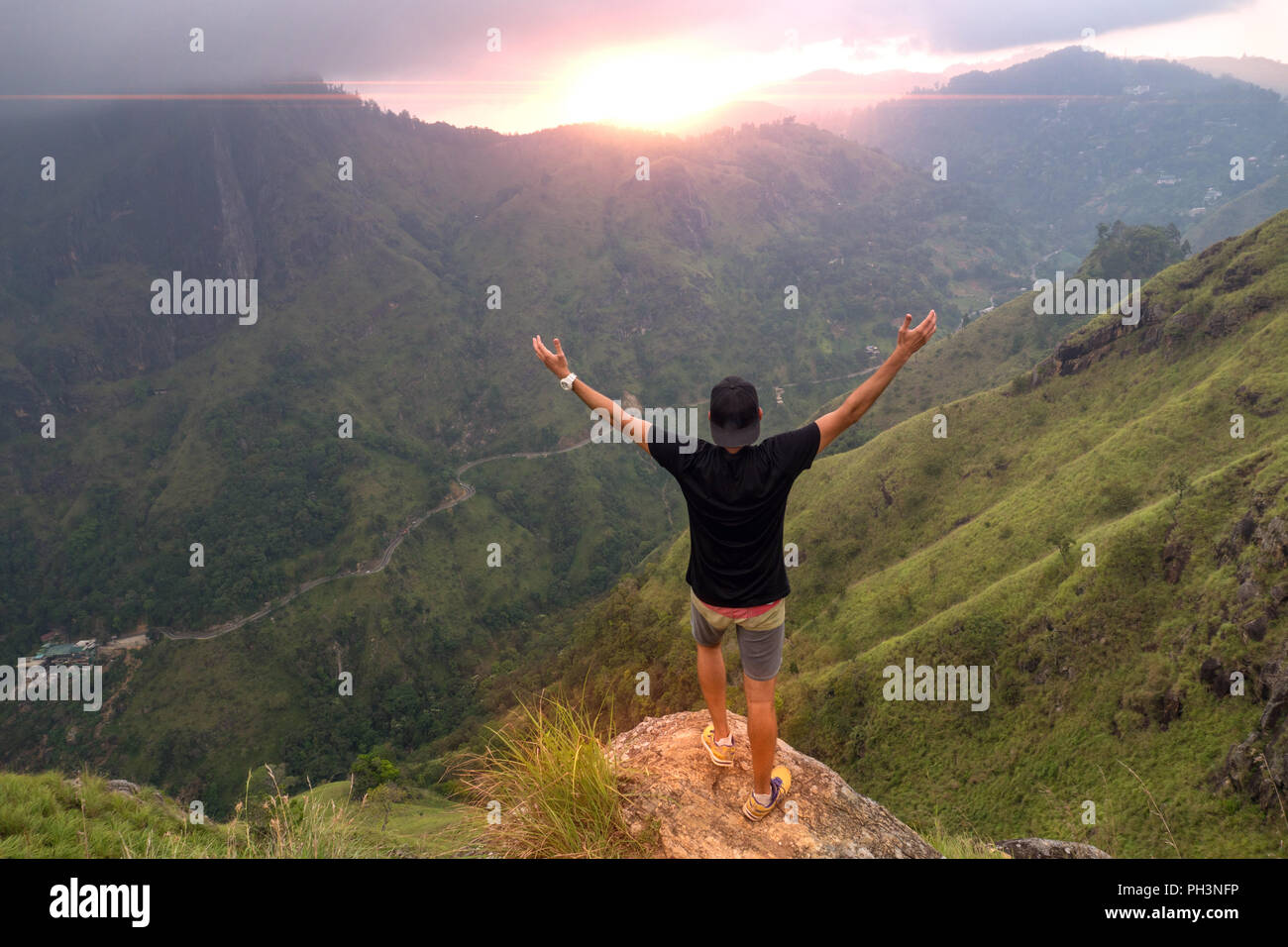 Hiker standing on top of a mountain with raised hands and enjoying ...