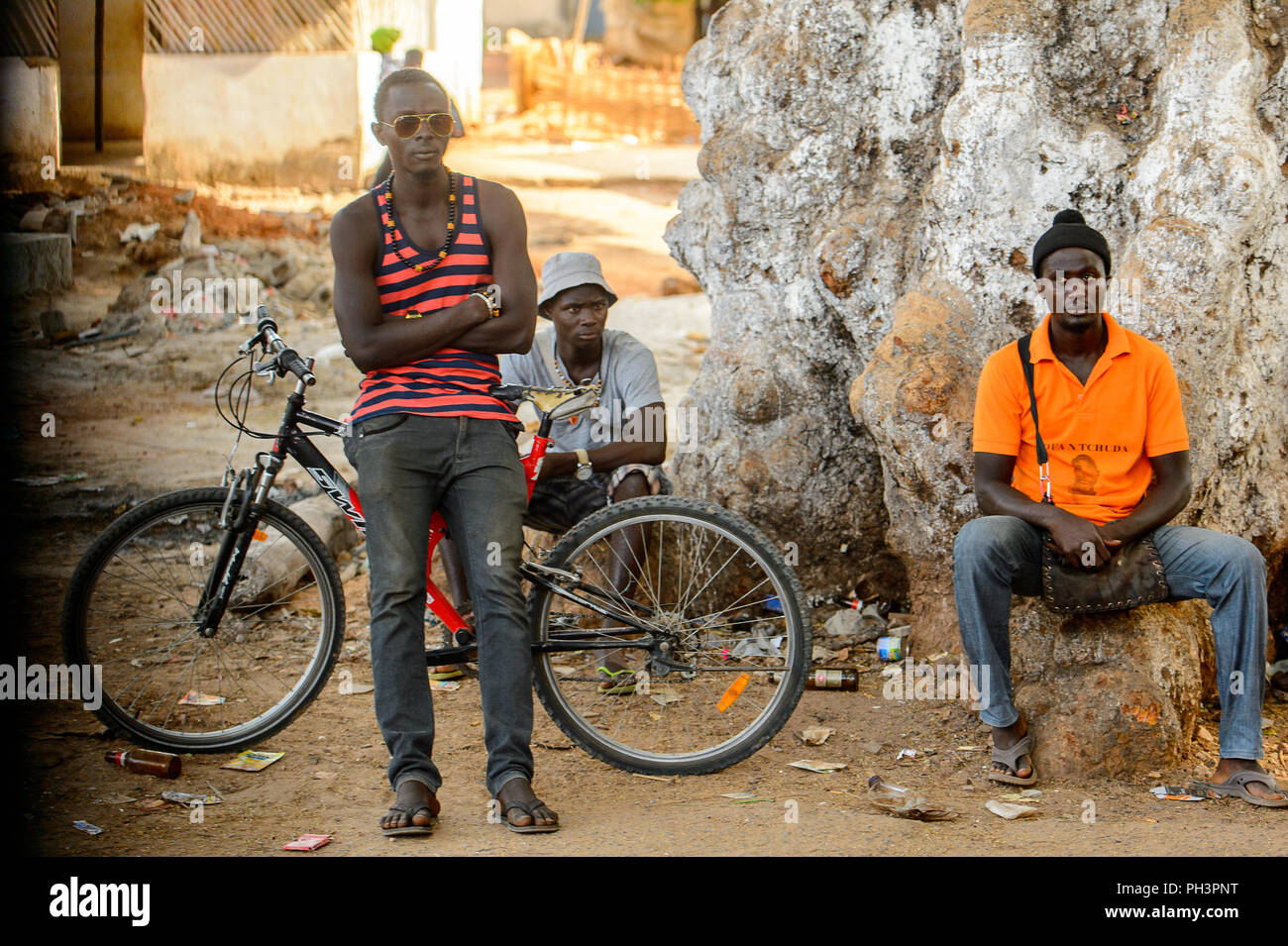 ROAD TO BISSAU, GUINEA B. - MAY 1, 2017: Unidentified local man leans on the bicycle in a village in Guinea Bissau. Still many people in the country l Stock Photo