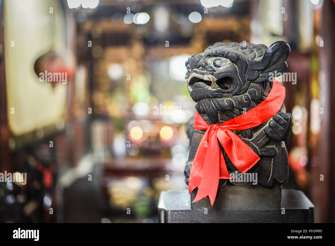Smart black stone lion statue glance at the right side, red scarf and blur background Stock Photo