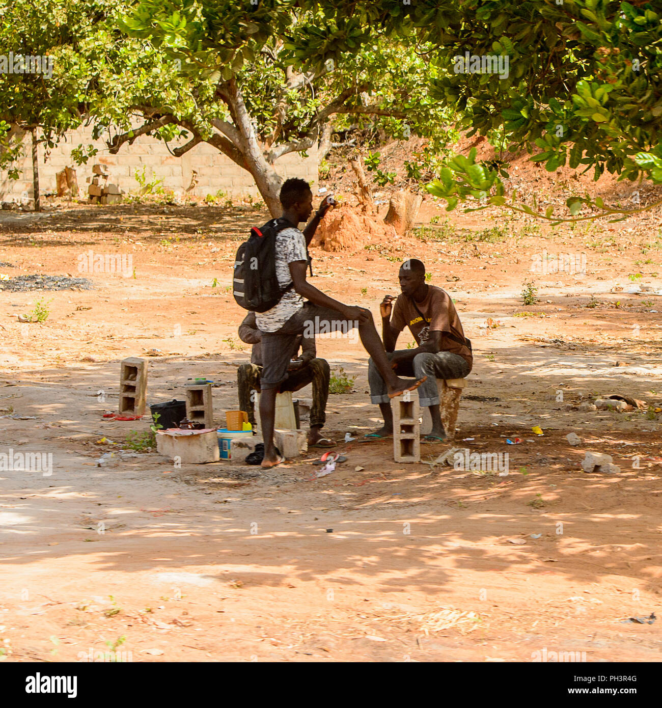 ROAD TO BISSAU, GUINEA B. - MAY 1, 2017: Unidentified local men talk about something in a village in Guinea Bissau. Still many people in the country l Stock Photo