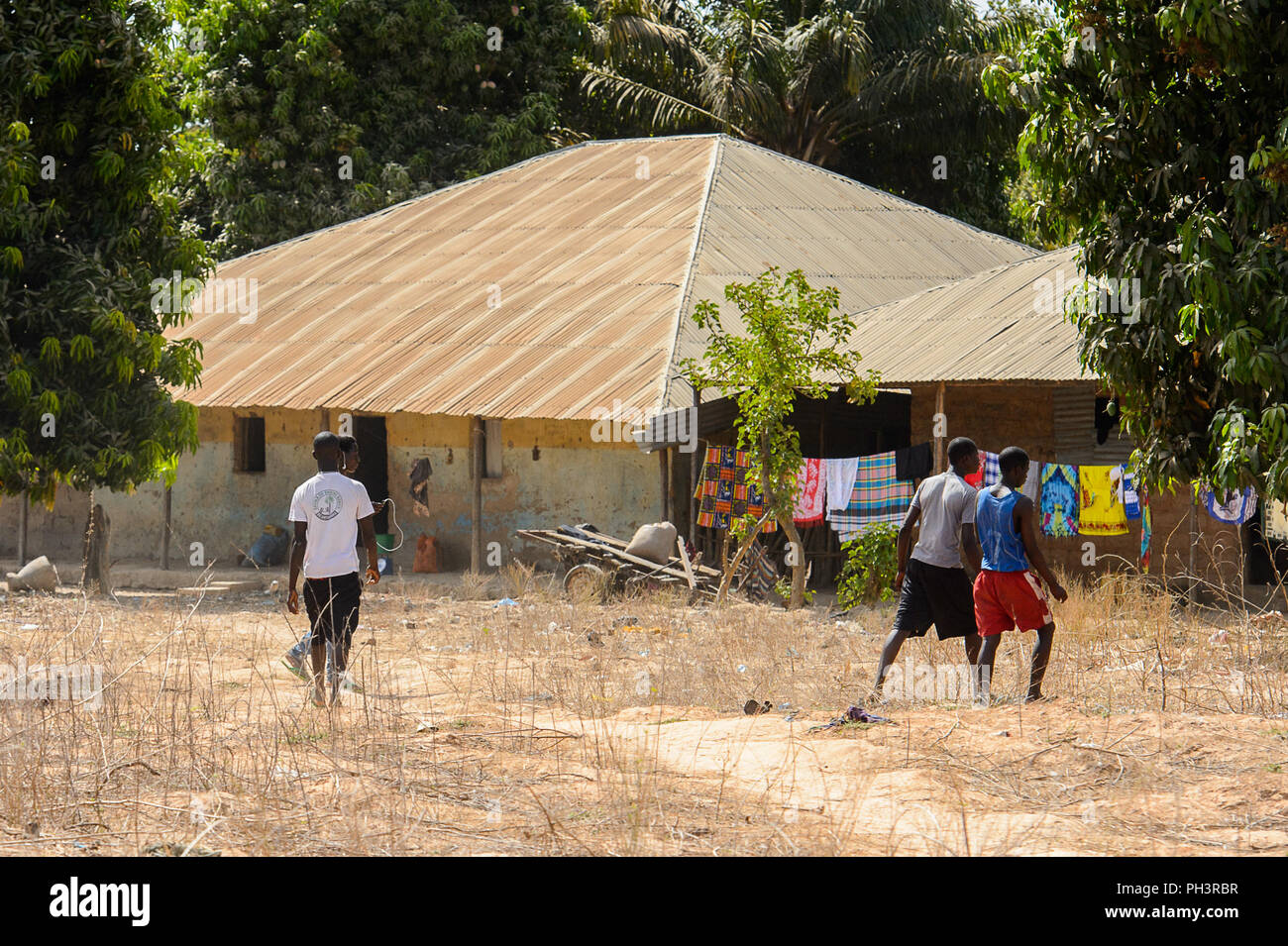 ROAD TO BISSAU, GUINEA B. - MAY 1, 2017: Unidentified local boys walk near the house in a village in Guinea Bissau. Still many people in the country l Stock Photo