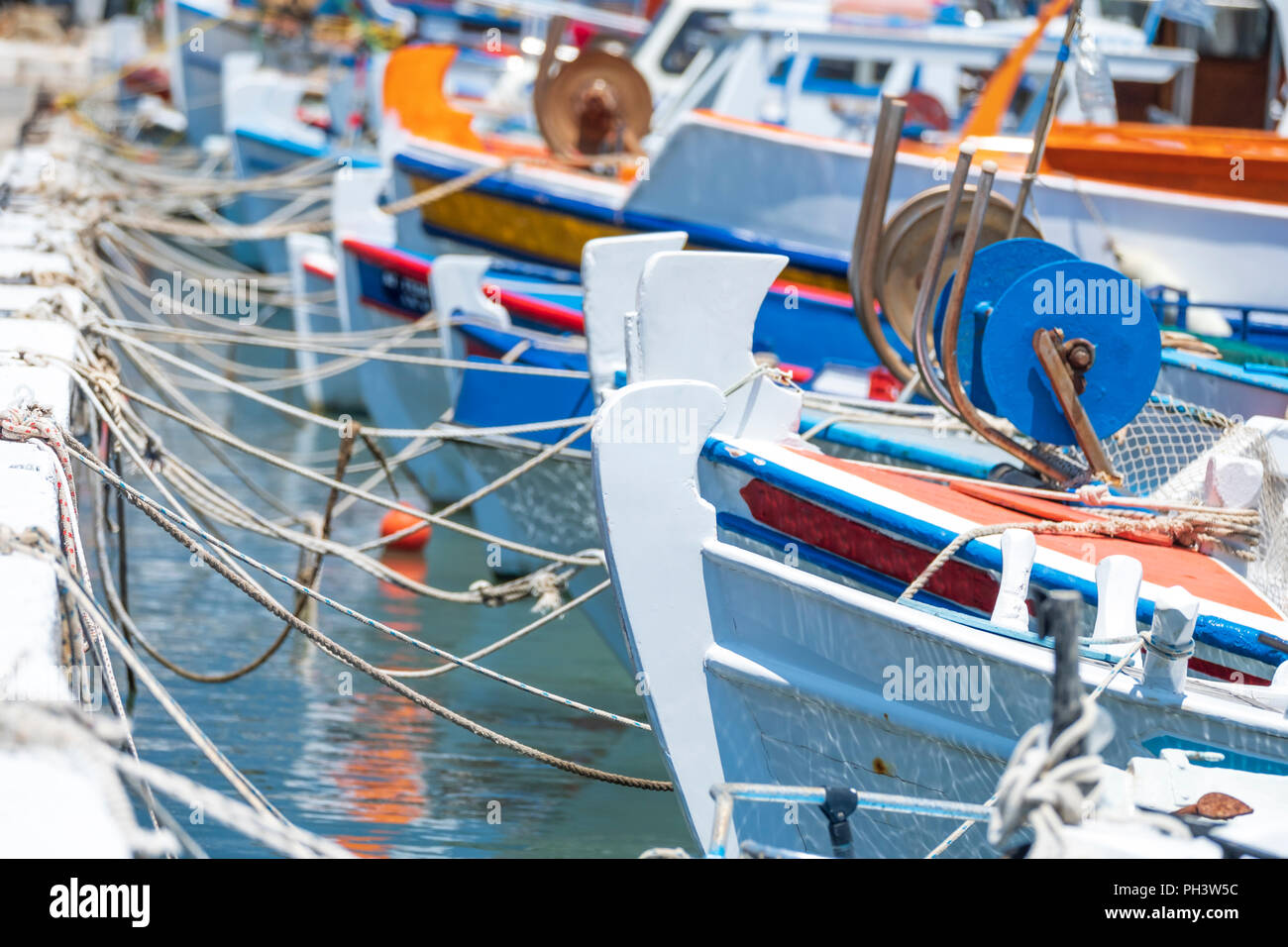small colorful Greek fishing boats are tied up with rope in a small tourist port in Greece Stock