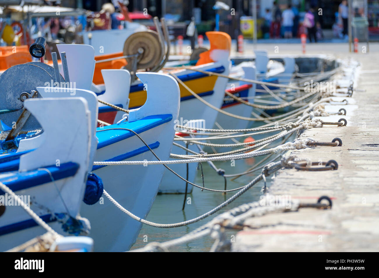 small colorful Greek fishing boats are tied up with rope in a small tourist port in Greece Stock