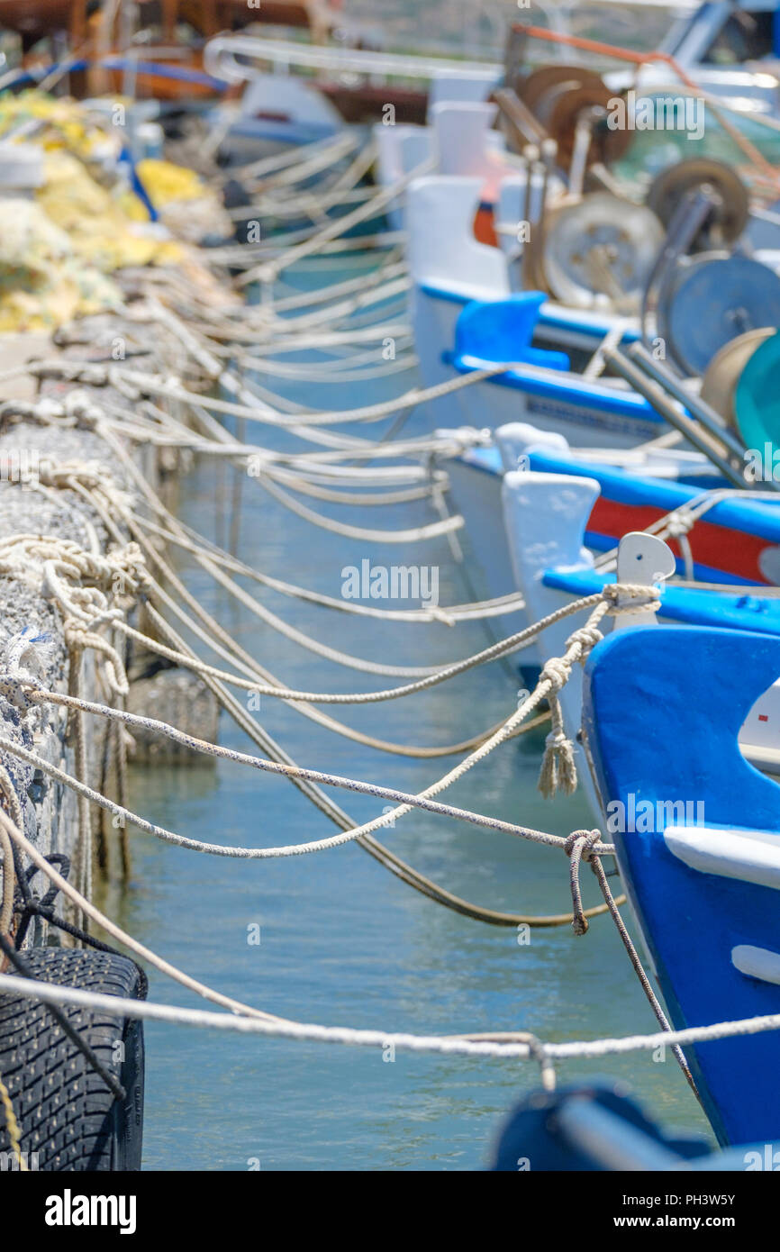 small colorful Greek fishing boats are tied up with rope in a small tourist port in Greece Stock
