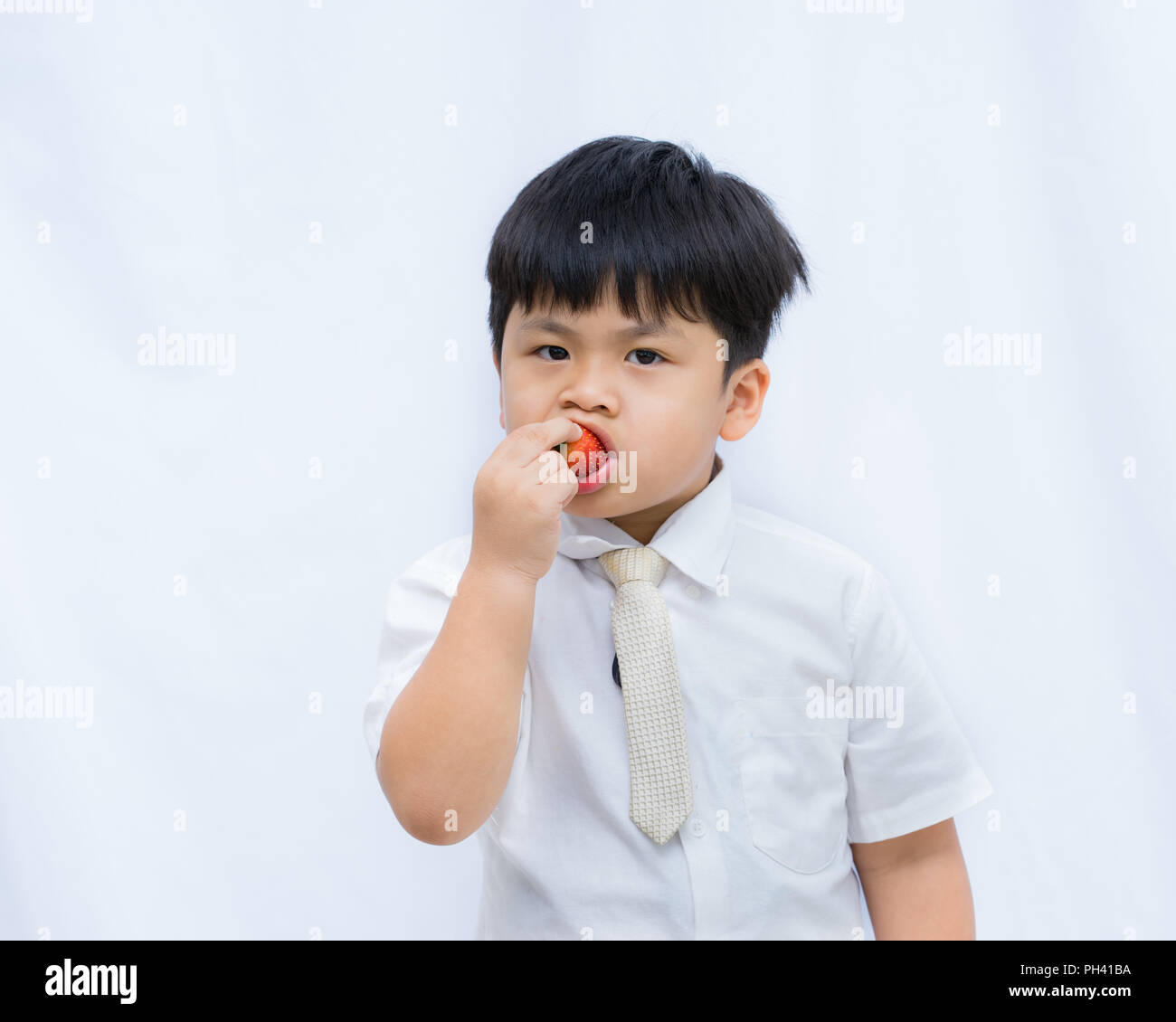 Portrait cute Asian boy eating red strawberry on white background, Stock Photo
