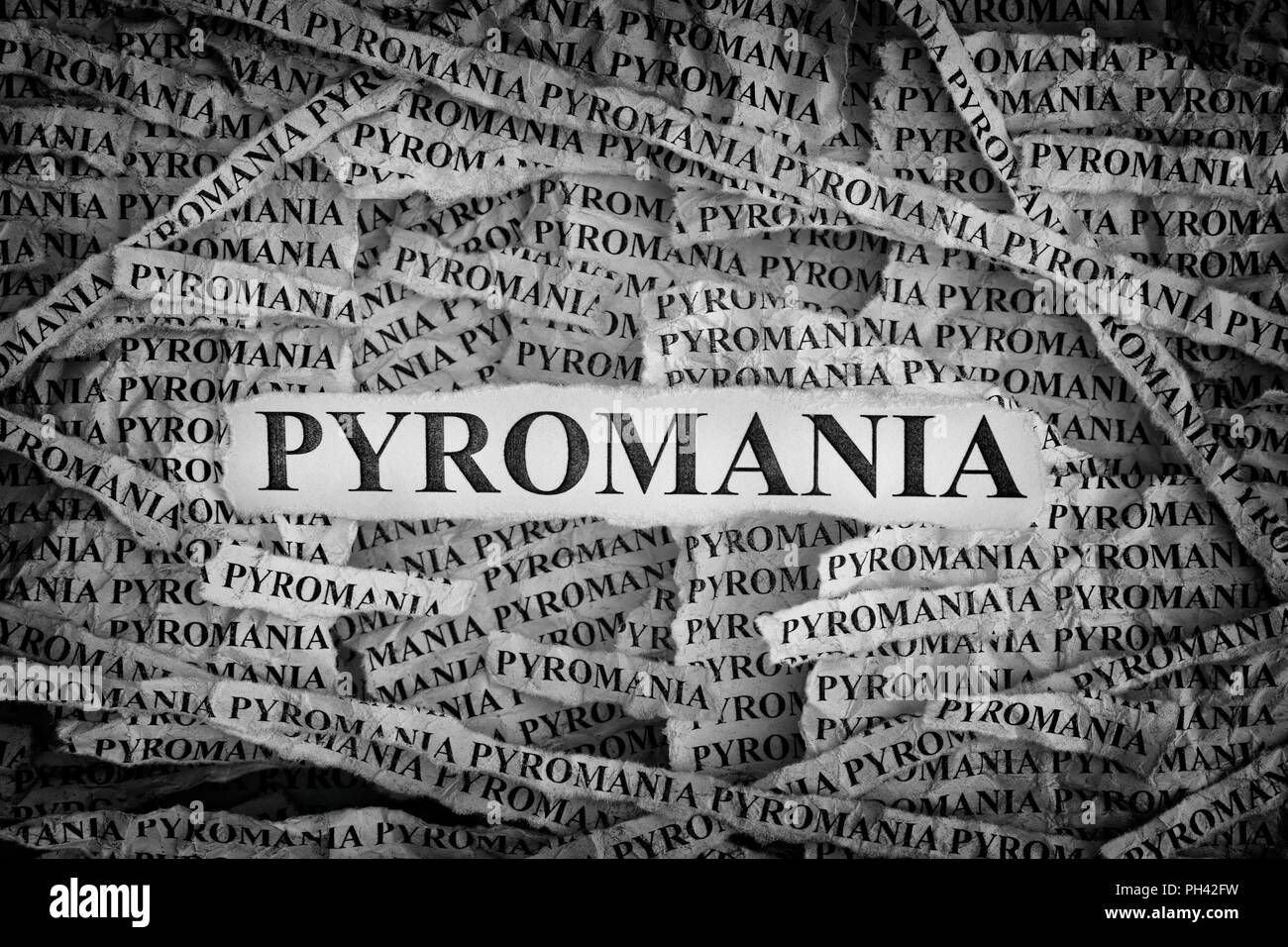Pyromania. Torn pieces of paper with the words Pyromania. Concept Image. Black and White. Closeup. Stock Photo