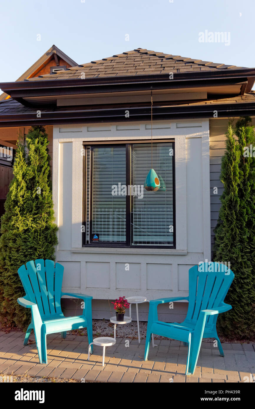 Two plastic Adirondack chairs on a summer patio outside a house Stock Photo