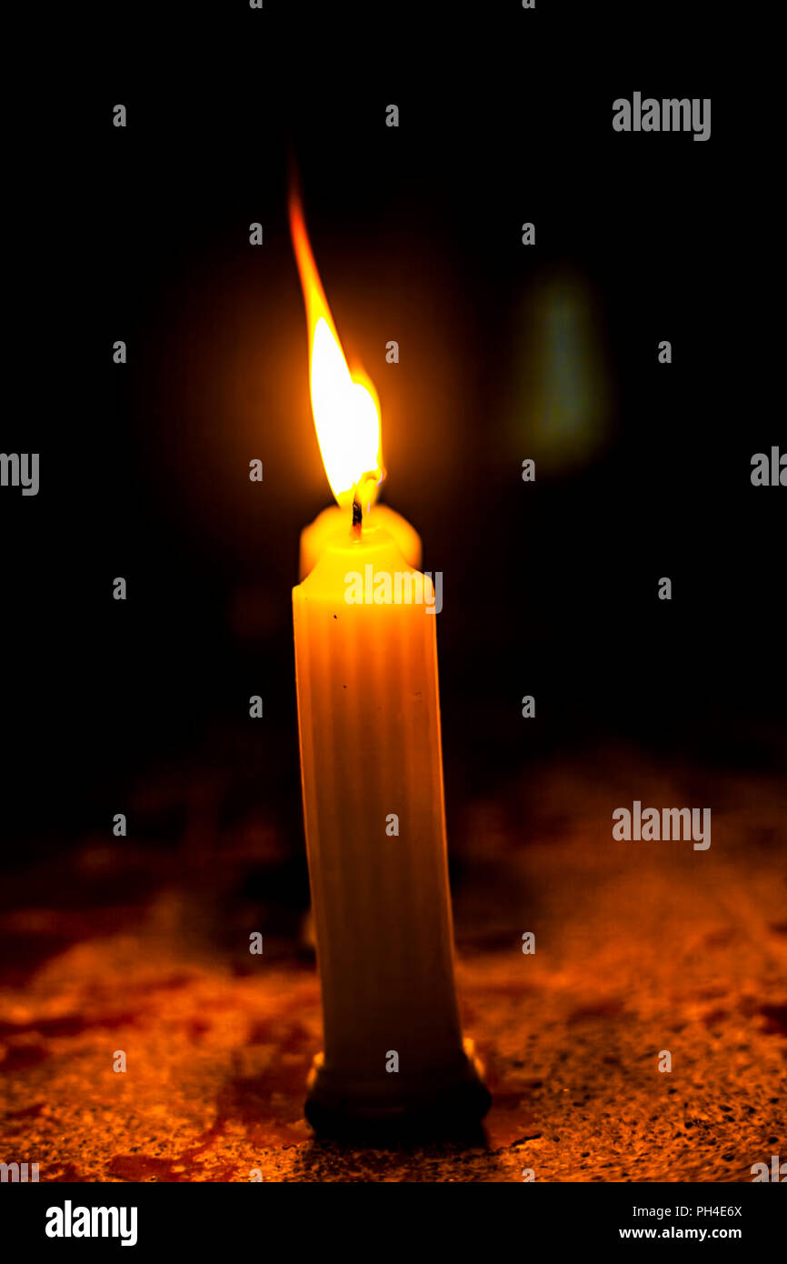 Single wax burning candle with a dark black background Stock Photo Alamy